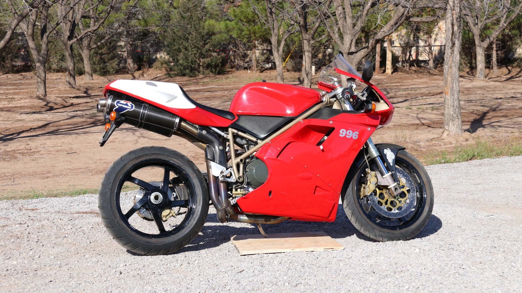 Red and white Ducati 996 motorcycle parked on a gravel road