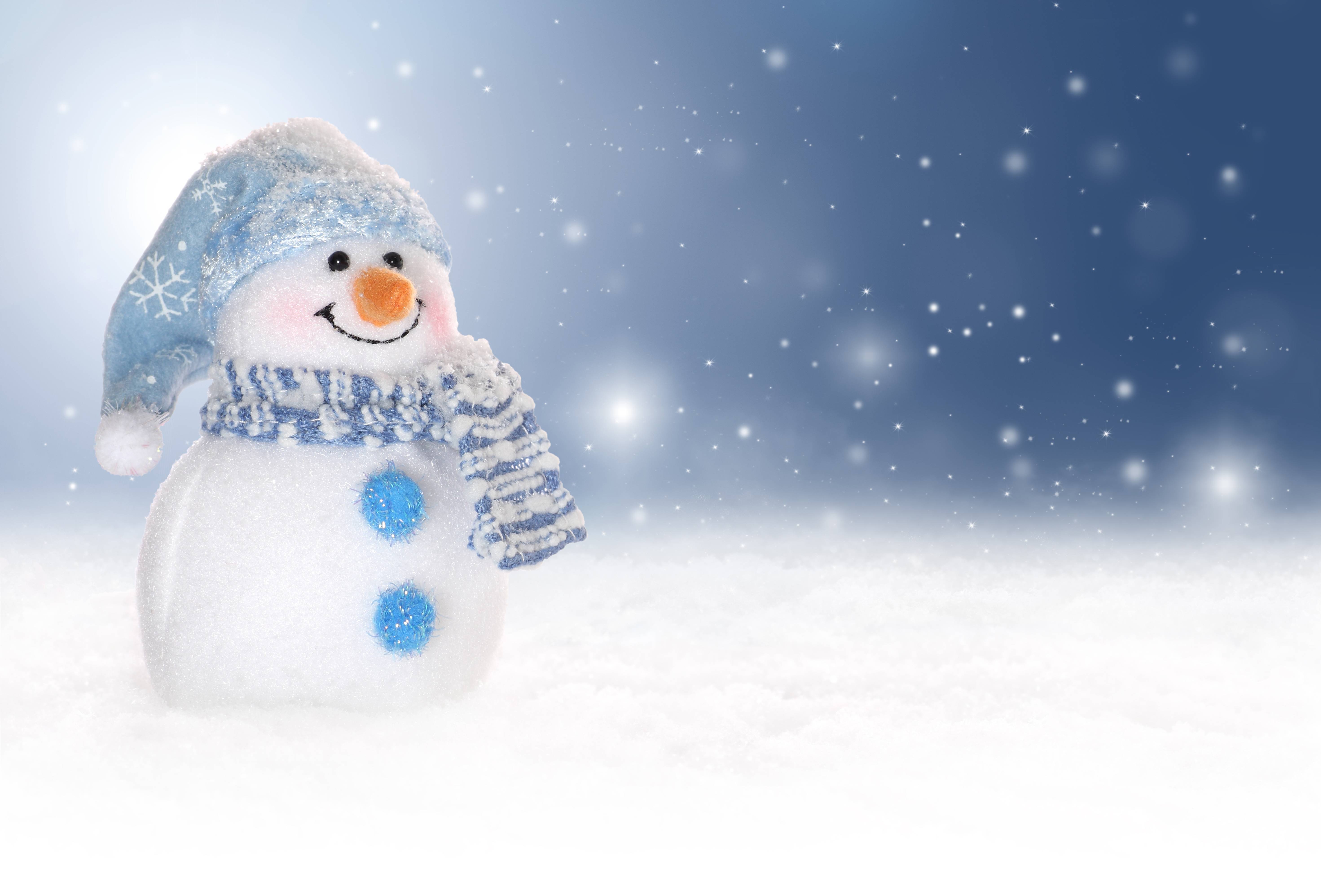 A cheerful snowman toy stands in a snowy landscape with falling snow, perfect for winter holiday themes