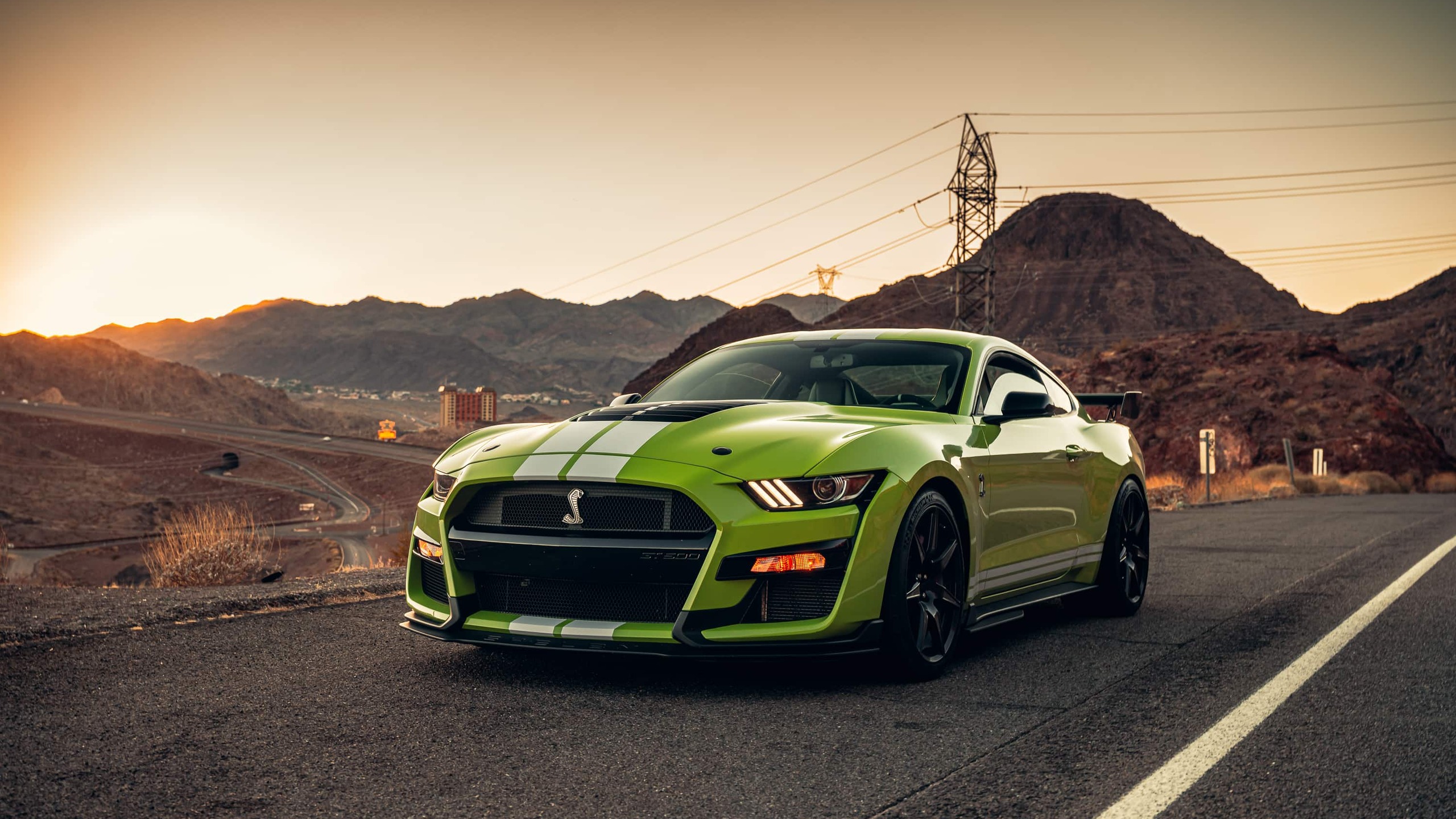 A vibrant green Ford Mustang Shelby GT500 parked on a desert road during sunset