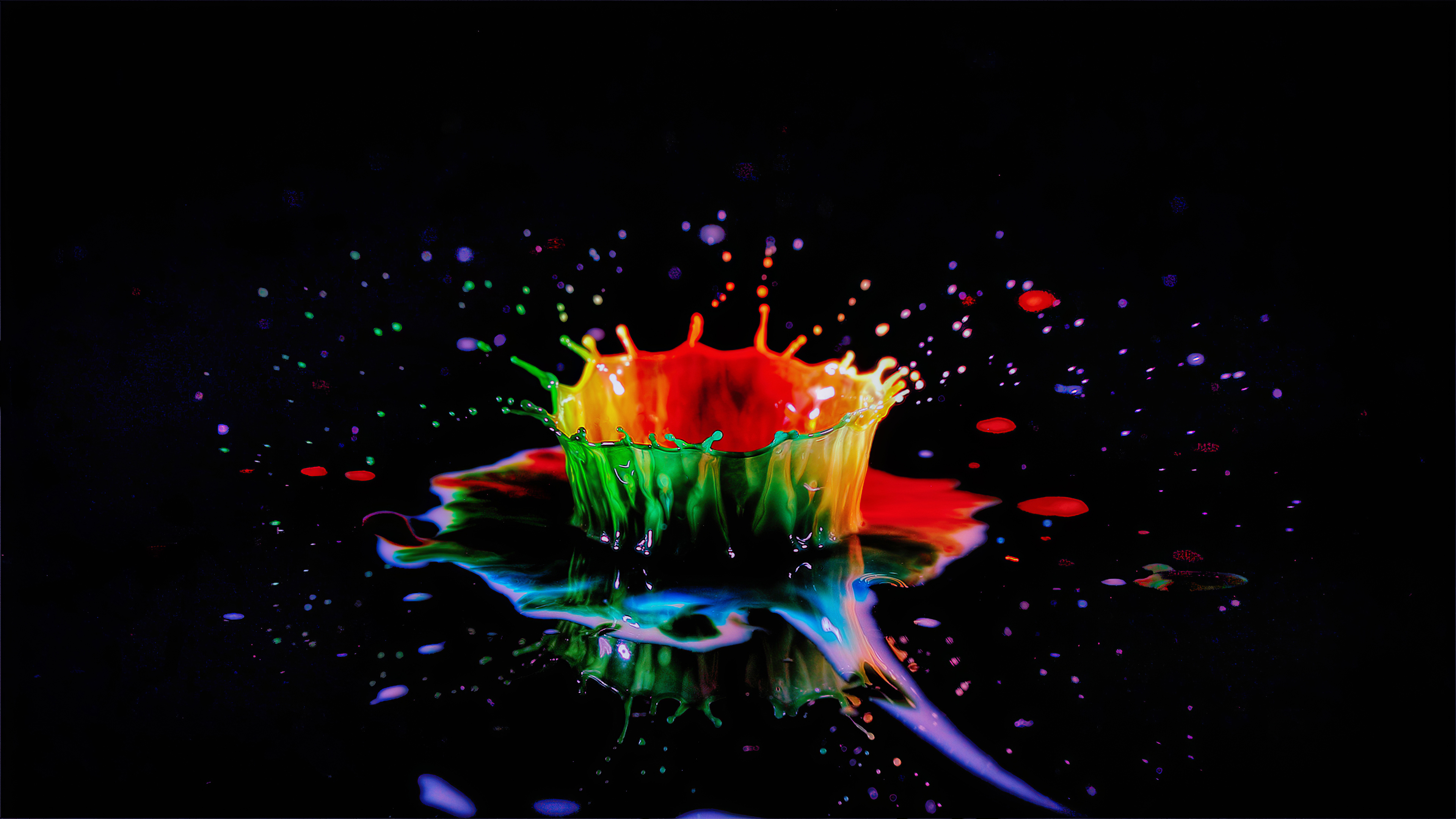 A vibrant splash of colorful paint, captured in 4k resolution against a black background. The paint forms a crown-like shape as it explodes outwards, creating an abstract and artistic image