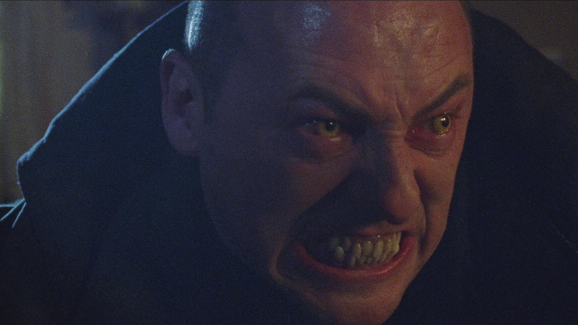 Close-up of Nosferatu from the 2024 film, with menacing yellow eyes and bared teeth