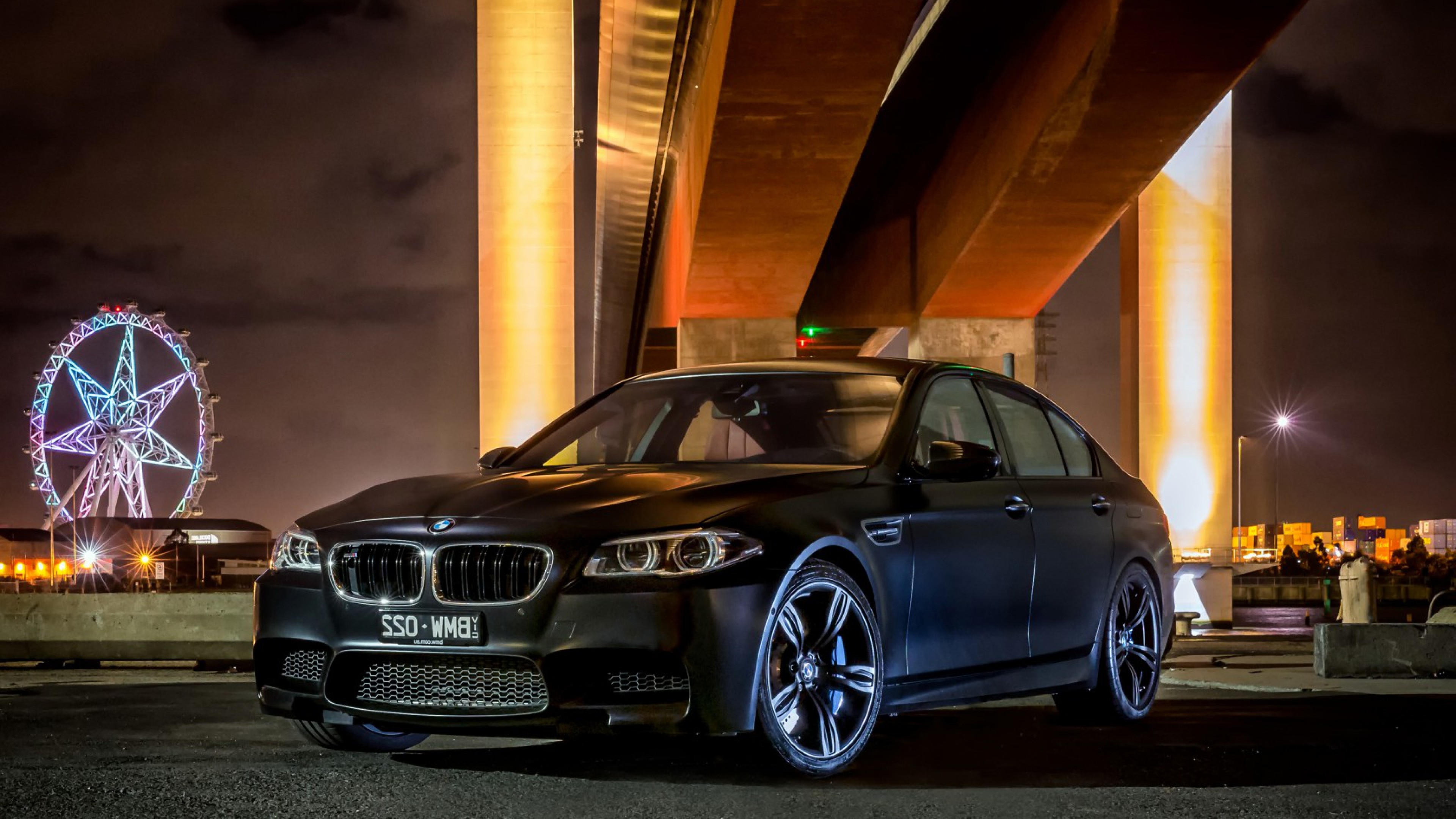 Sleek Black BMW M5 parked under a bridge at night