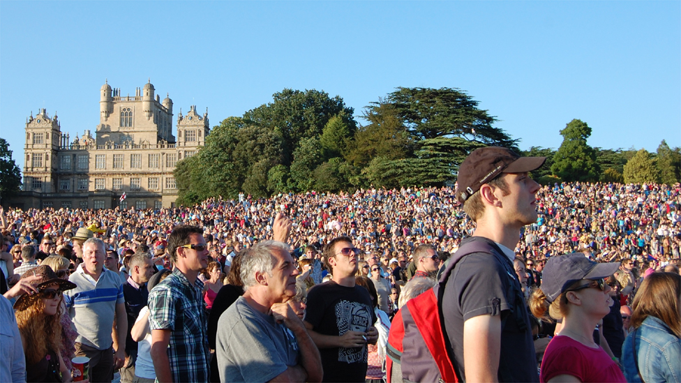 People In The Crowd At Splendour With Wollaton Hall Background