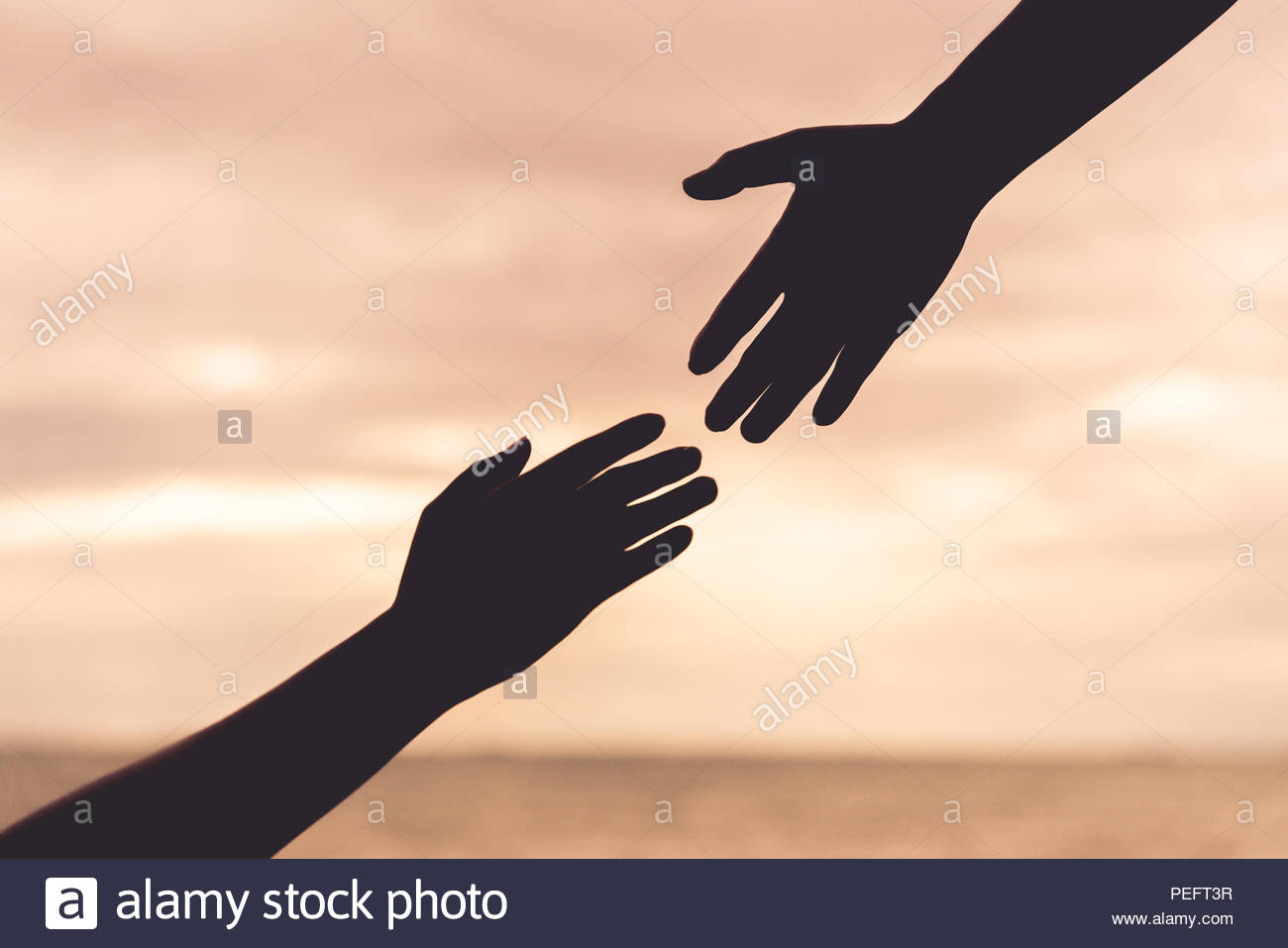 Silhouette Helping Hands On Blurred Sea And Sky Background