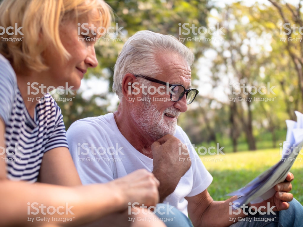 Senior Couple Sitting Beside Each Other In The Park Read A Book