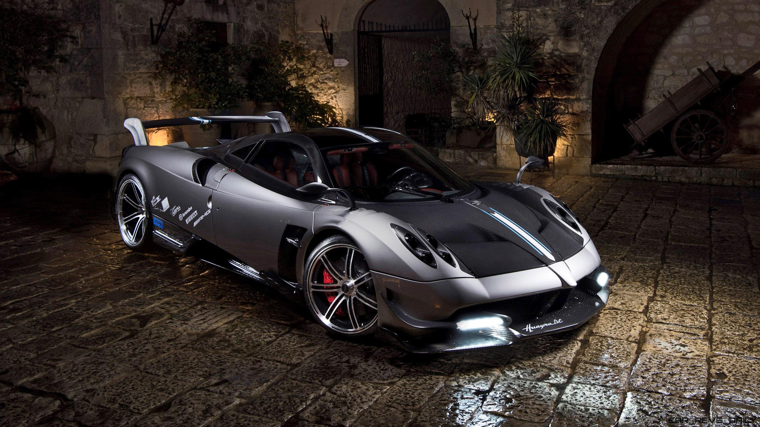 A sleek, silver Pagani Huayra supercar parked on a cobblestone courtyard at night
