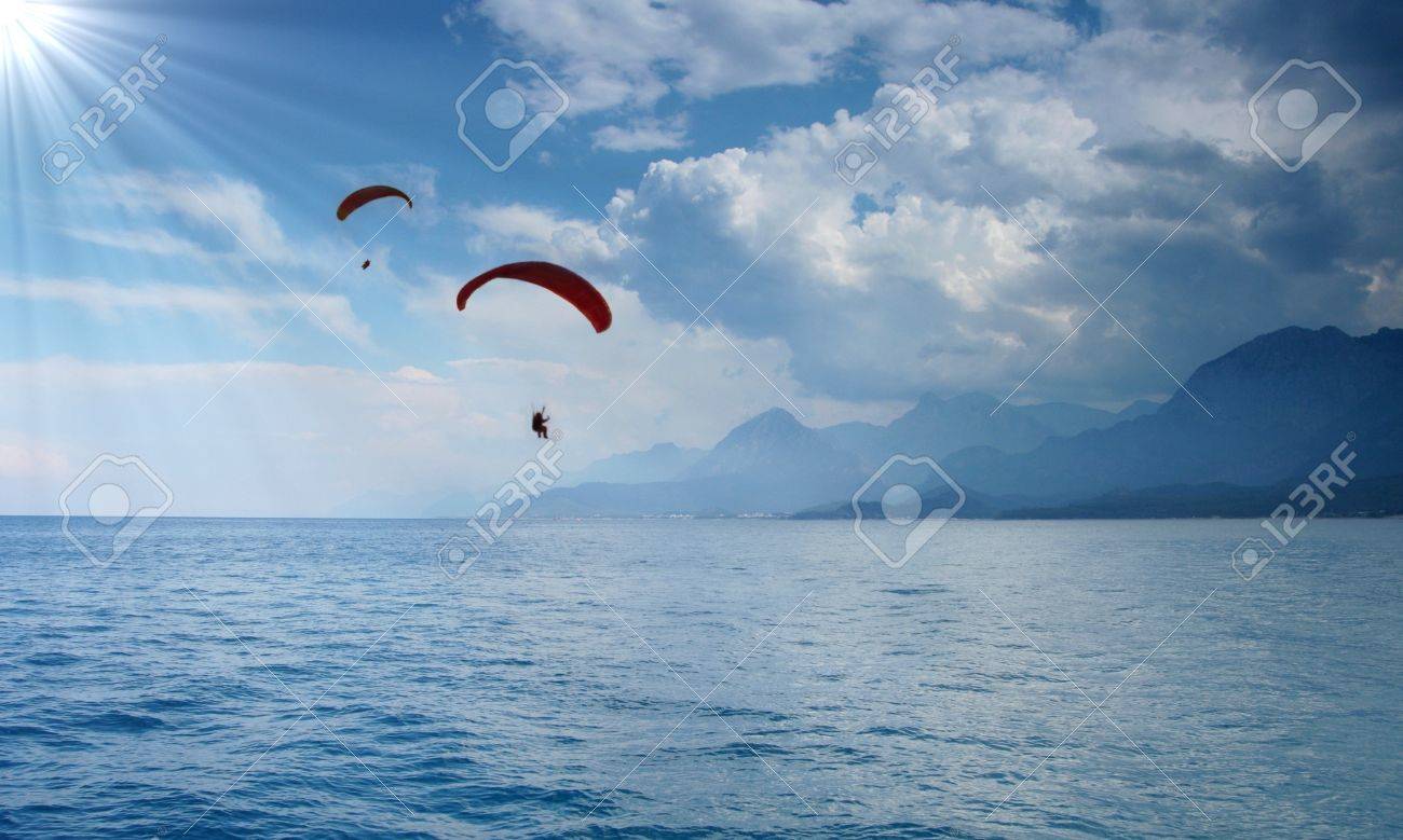 Two Paragliders Silhouettes On Beautiful Coastline Background
