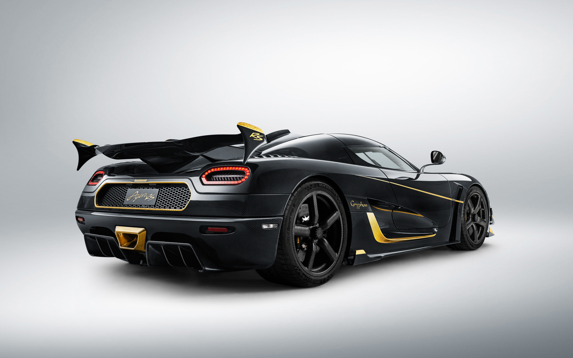 Rear view of a black Koenigsegg Agera RS Gryphon with gold accents, highlighting its sleek design and aerodynamic features