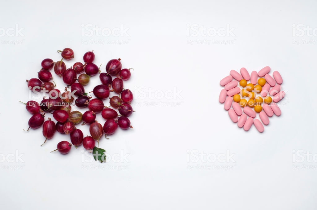 Bunch Of Gooseberries And Vitamin Pills On A White Background