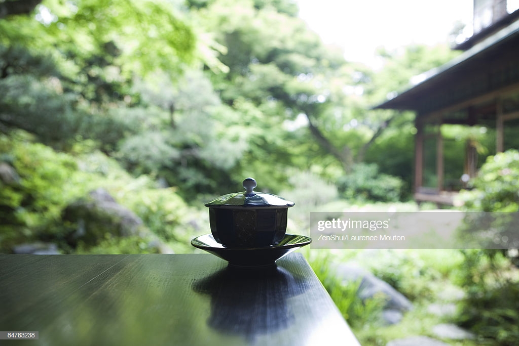 Covered Tea Cup And Saucer On Table Japanese Garden In Background