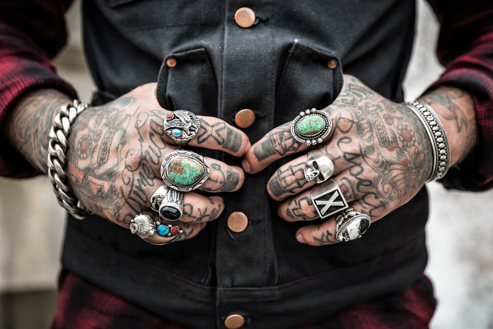 Close-up of tattooed hands with multiple rings, showcasing intricate ink designs and various silver jewelry