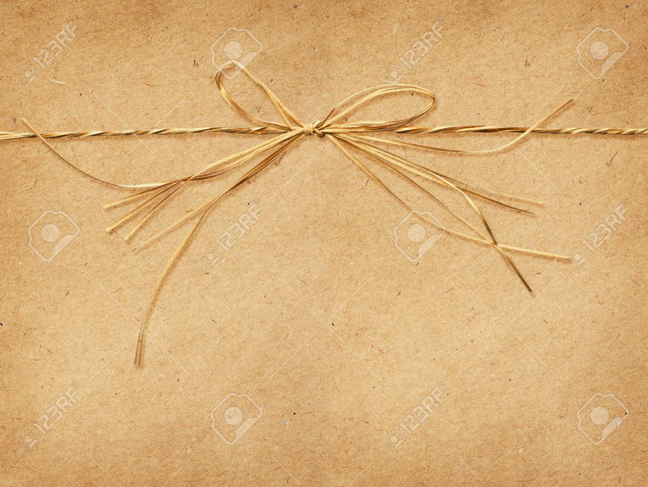 Beige Raffia Bow Tied On Craft Paper Background Stock Photo