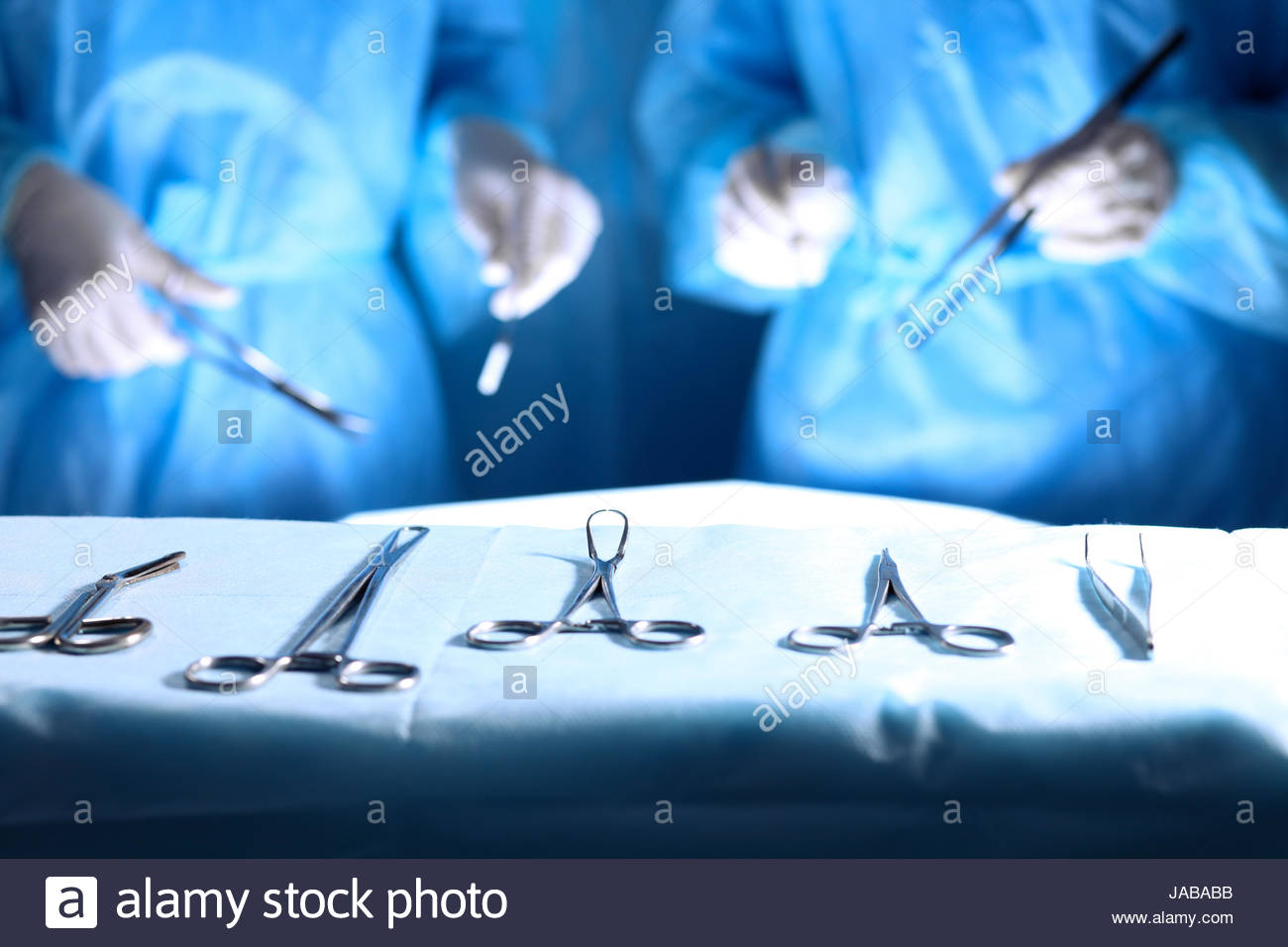 Surgical Tools Lying On The Table While Group Of Surgeons At Stock