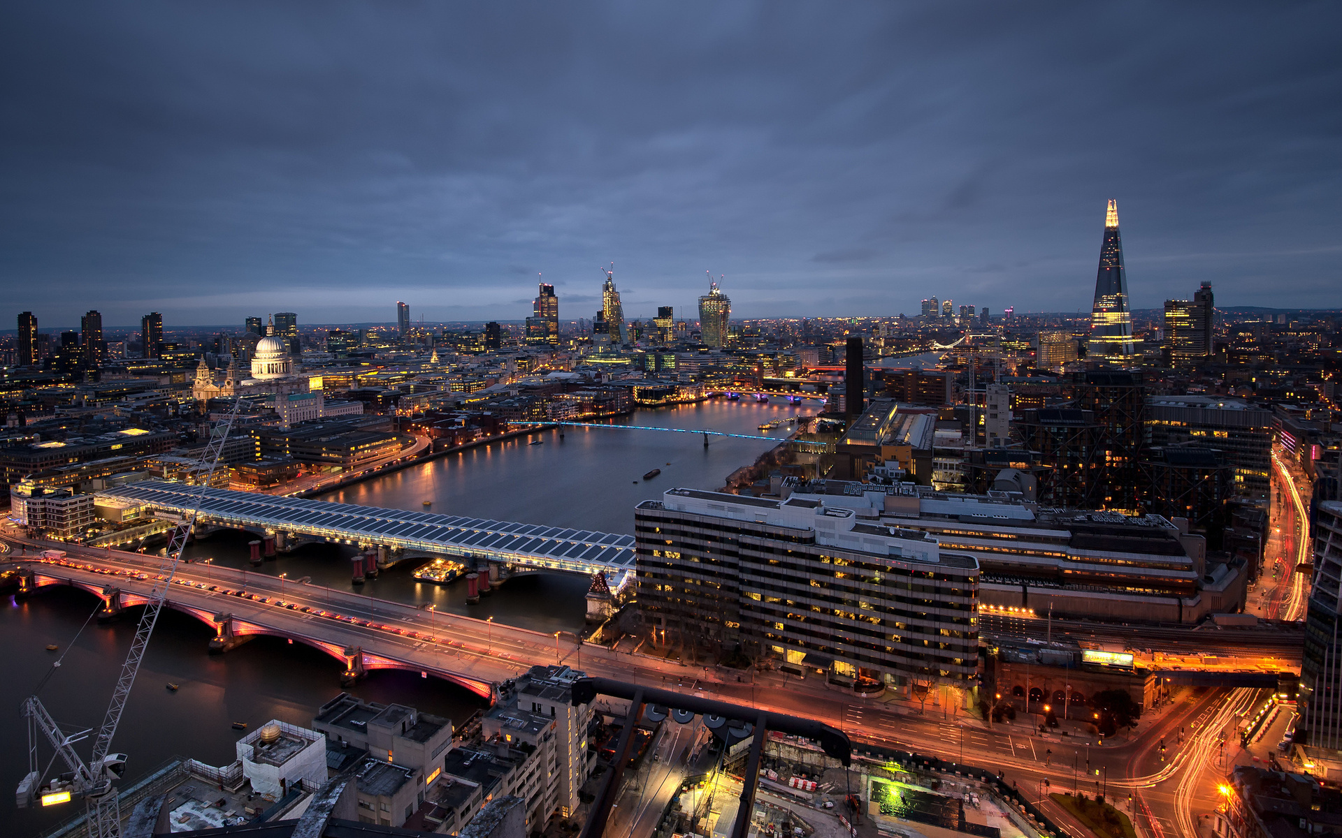 A stunning aerial view of the London skyline at dusk, featuring iconic landmarks like the Shard, St. Paul's Cathedral, and the Millennium Bridge