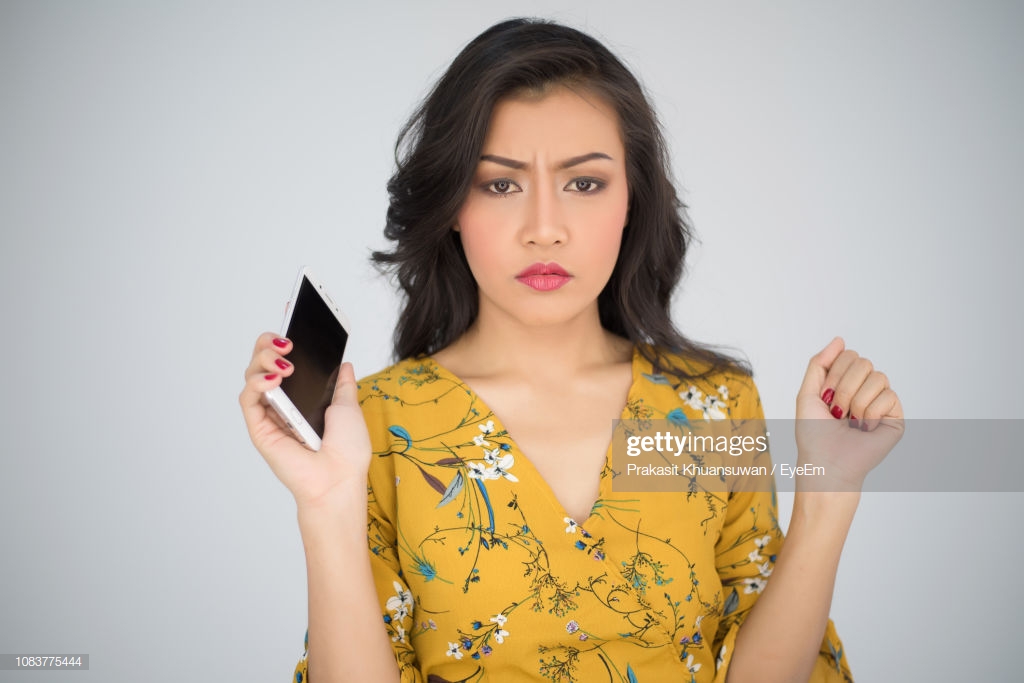 Portrait Of Beautiful Worried Woman Holding Smart Phone Against