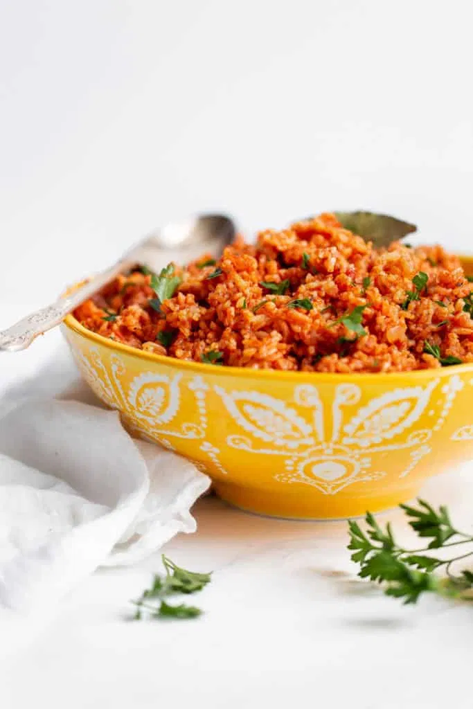 Jollof Rice Recipe Served In A Yellow Bowl Against White