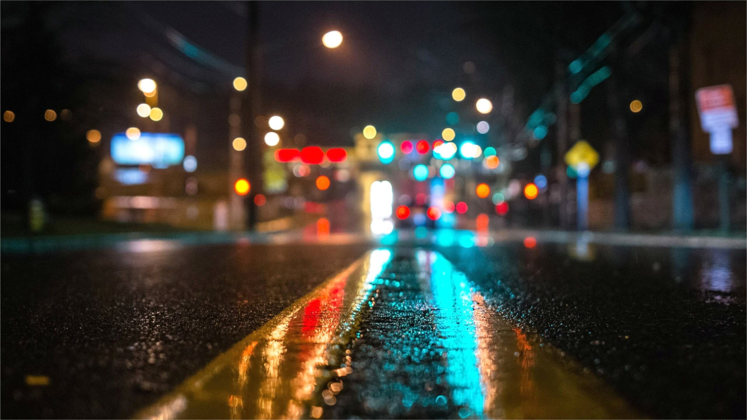 4K wallpaper of a wet city street at night, with colorful bokeh from streetlights and traffic