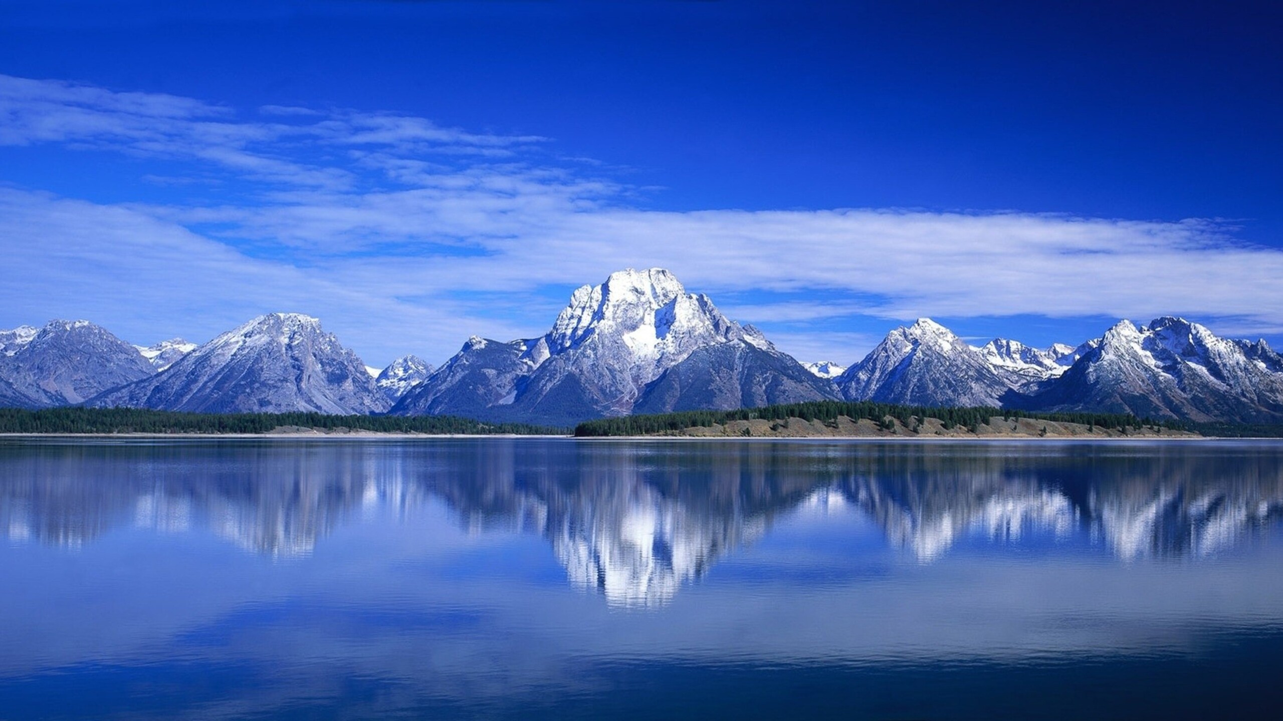 Serene mountain range reflected in a calm lake under a clear blue sky
