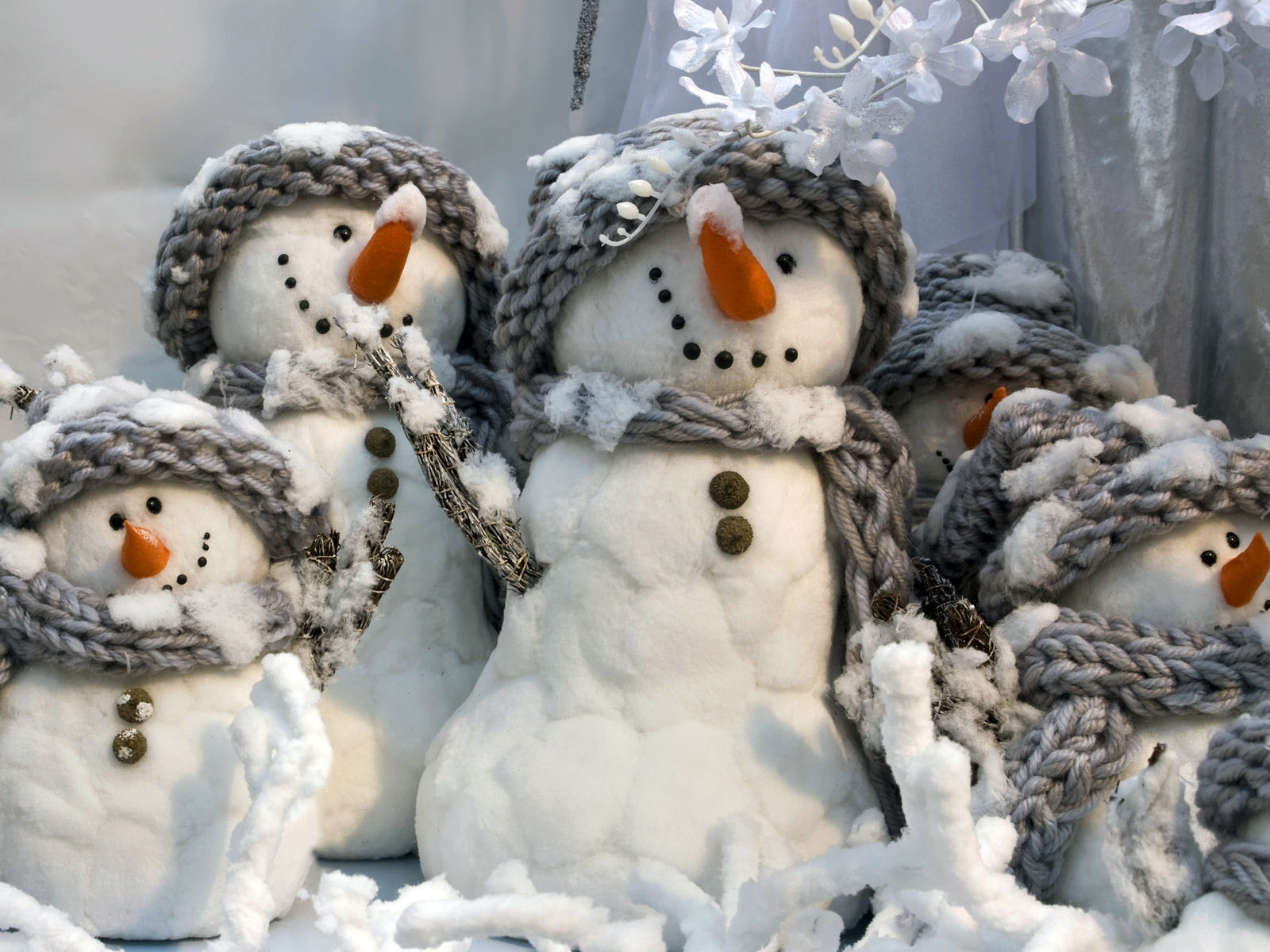 A charming collection of snowmen figurines, adorned with knitted hats and scarves, creating a festive winter scene