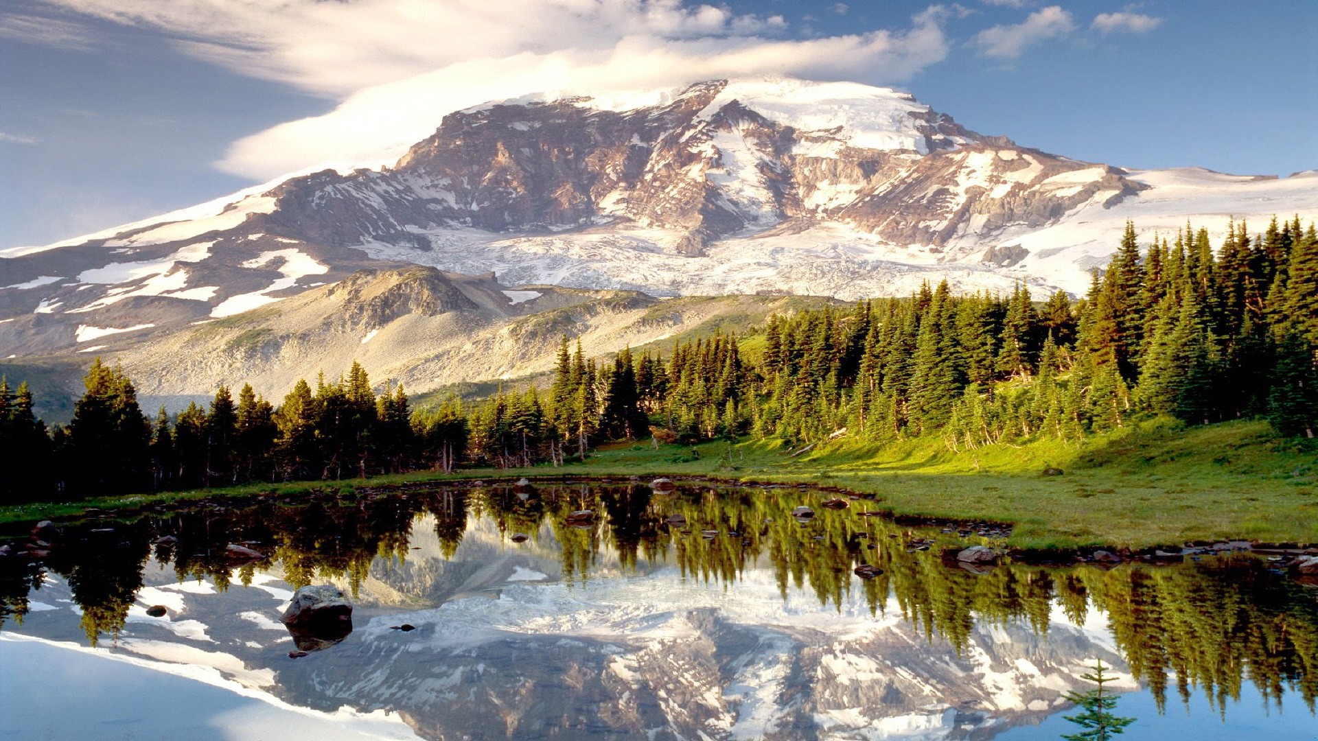 A stunning reflection of a snow-capped mountain in a calm alpine lake, surrounded by a lush evergreen forest