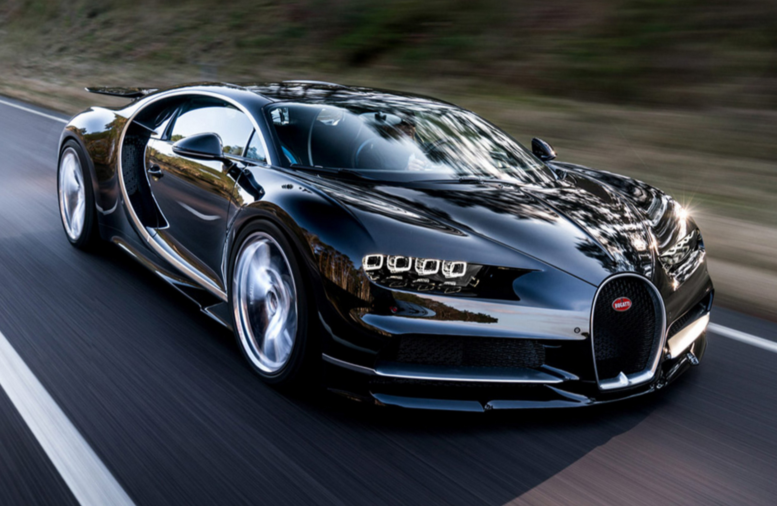 A sleek black Bugatti Chiron Super Sport speeds down a highway, showcasing its luxurious design and powerful performance