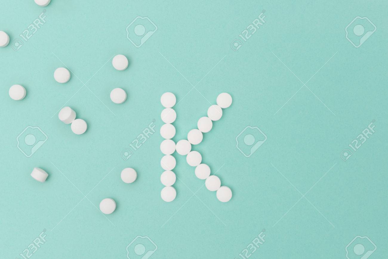 Vitamin K Pills Forming The Letter Over Turquoise Background