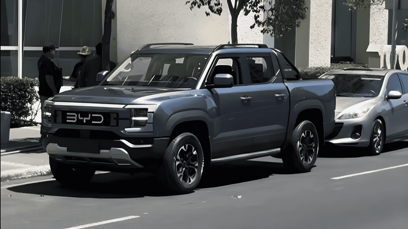 A sleek, dark gray BYD Shark pickup truck parked on a city street