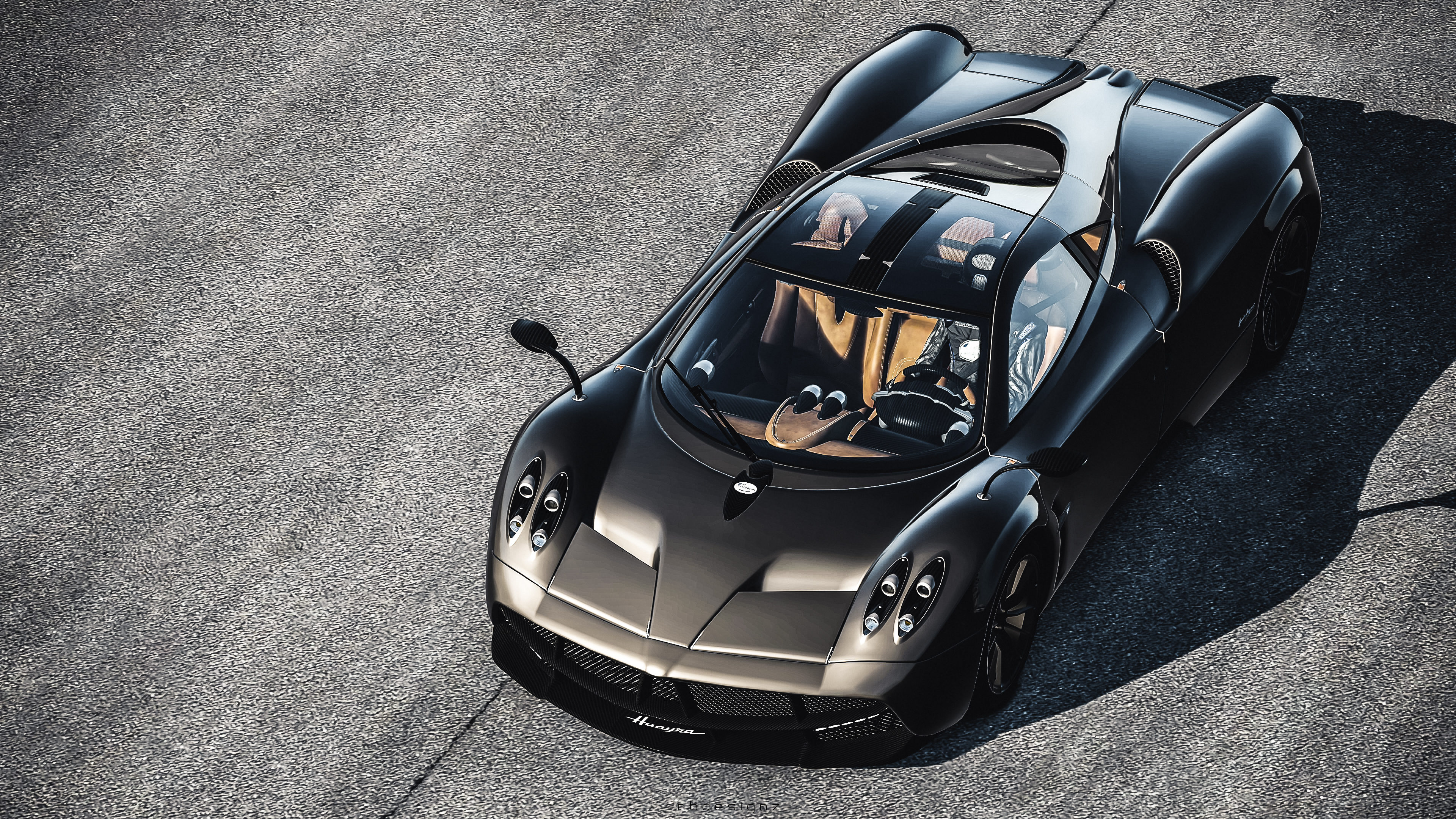 A top-down view of a sleek, dark gray Pagani Huayra, parked on an asphalt surface, showcasing its unique design and luxurious details