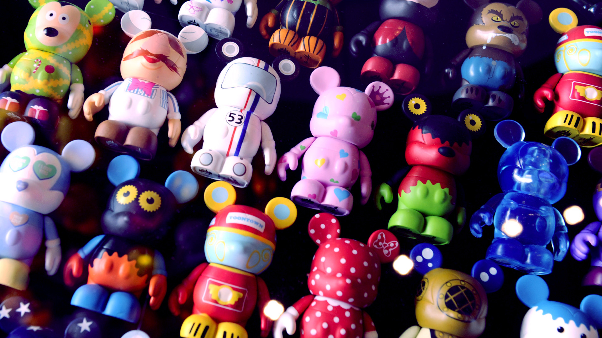 A collection of colorful Disney Vinylmation figures displayed on a dark surface