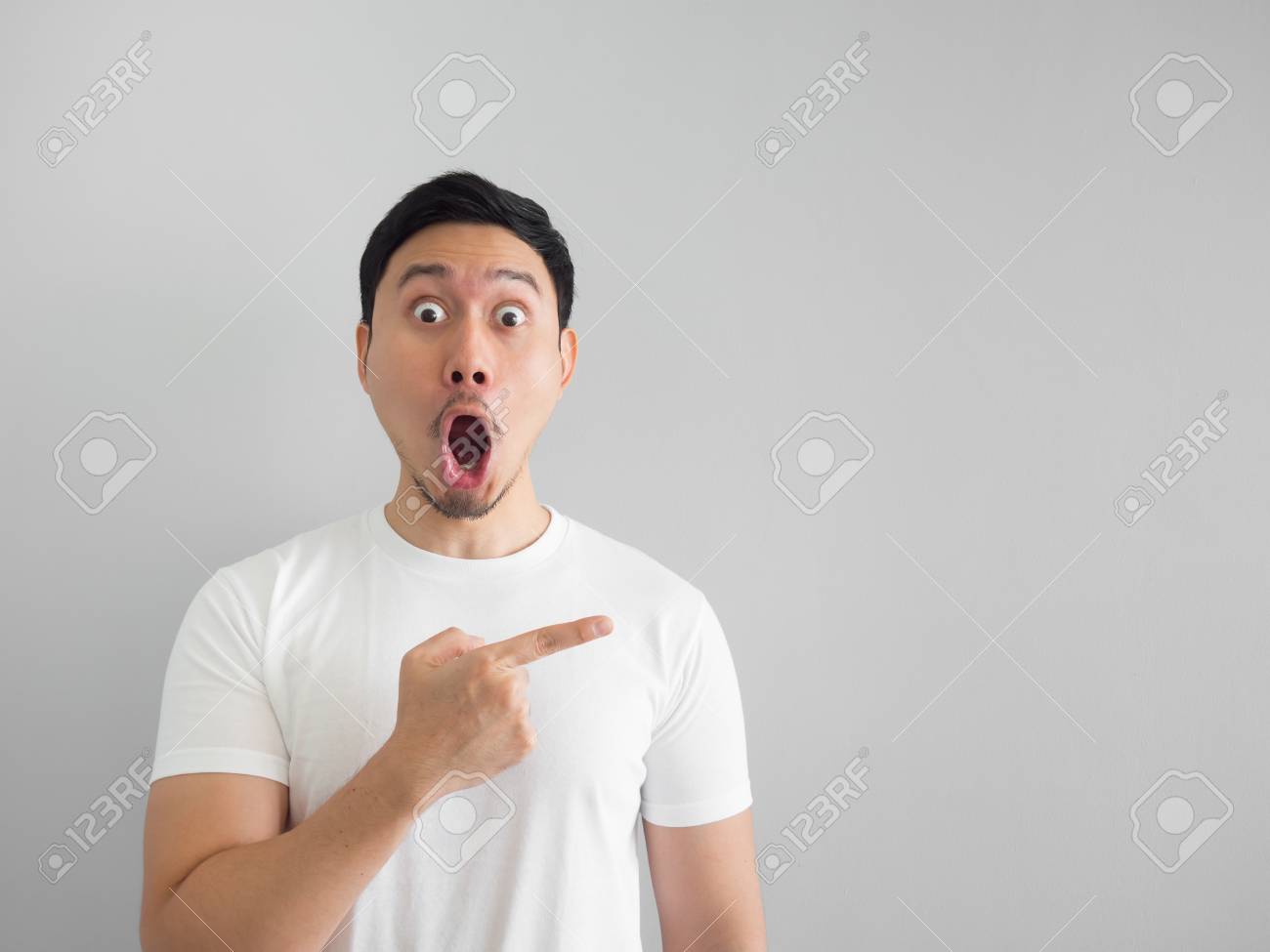Shocked Face Of Asian Man In White Shirt On Grey Background Stock