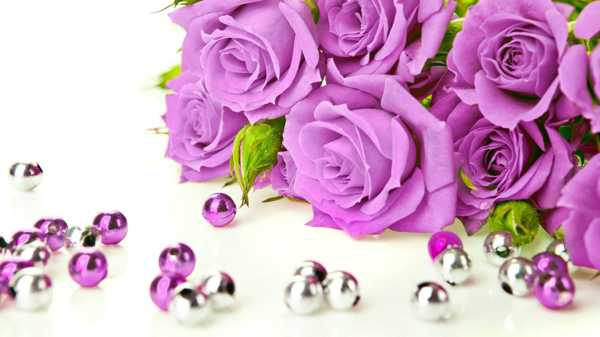 A beautiful bouquet of purple roses with scattered metallic beads on a white background