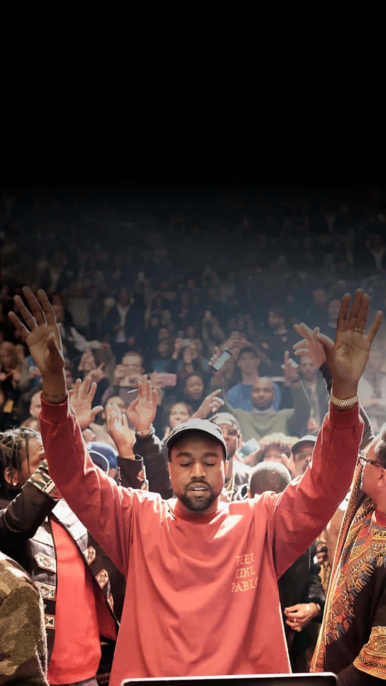 Download Kanye West At A Concert With His Hands Up Wallpaper