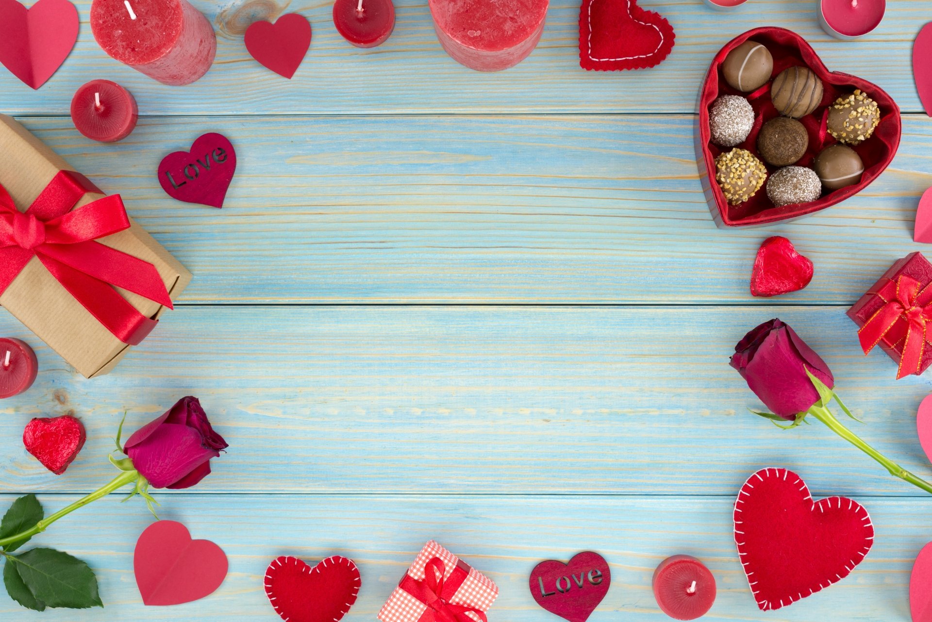 Valentine's Day background with gifts, roses, chocolates, and candles on a blue wooden table