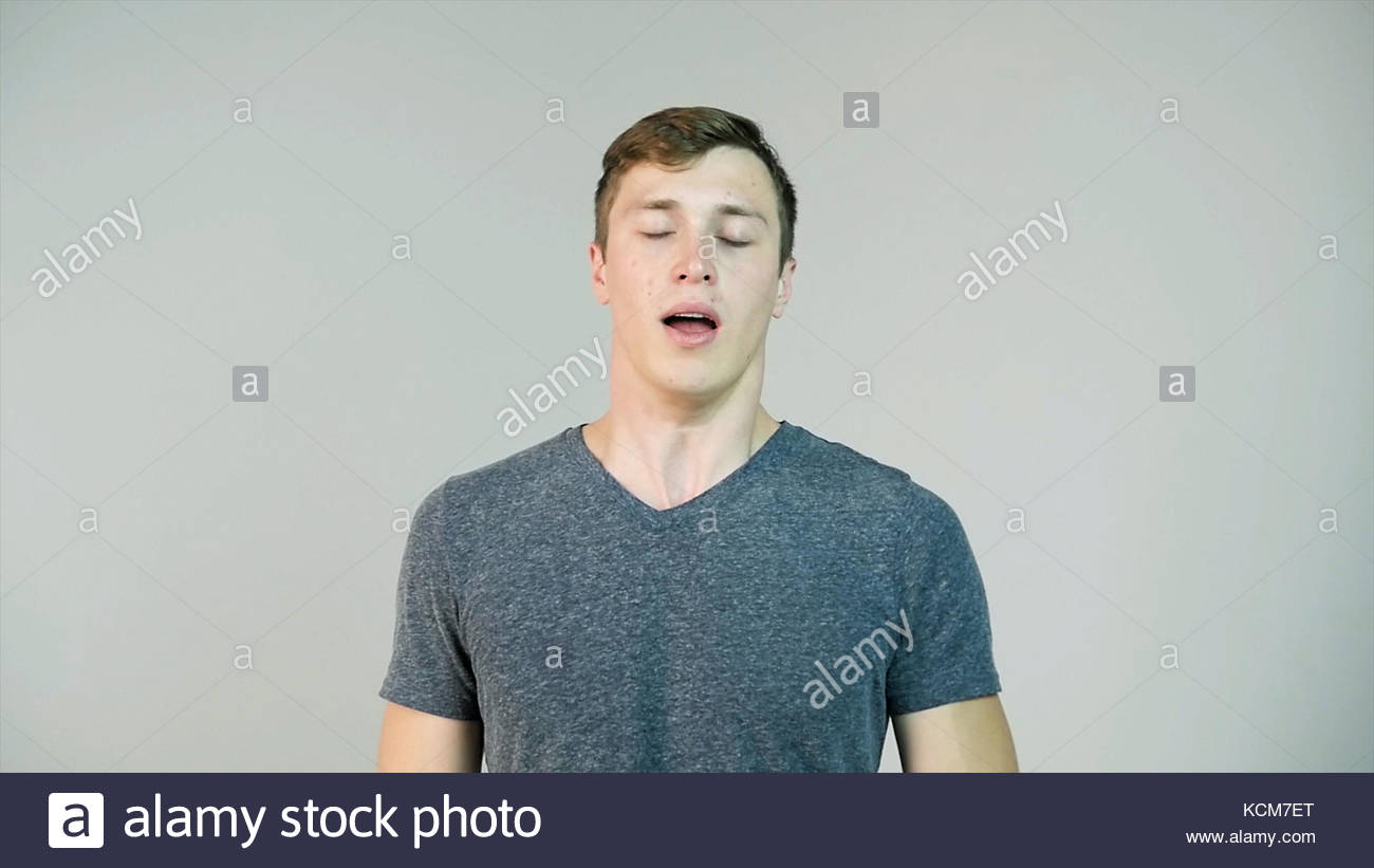 Young Man Sneezing On A White Background Slow Motion Stock Photo