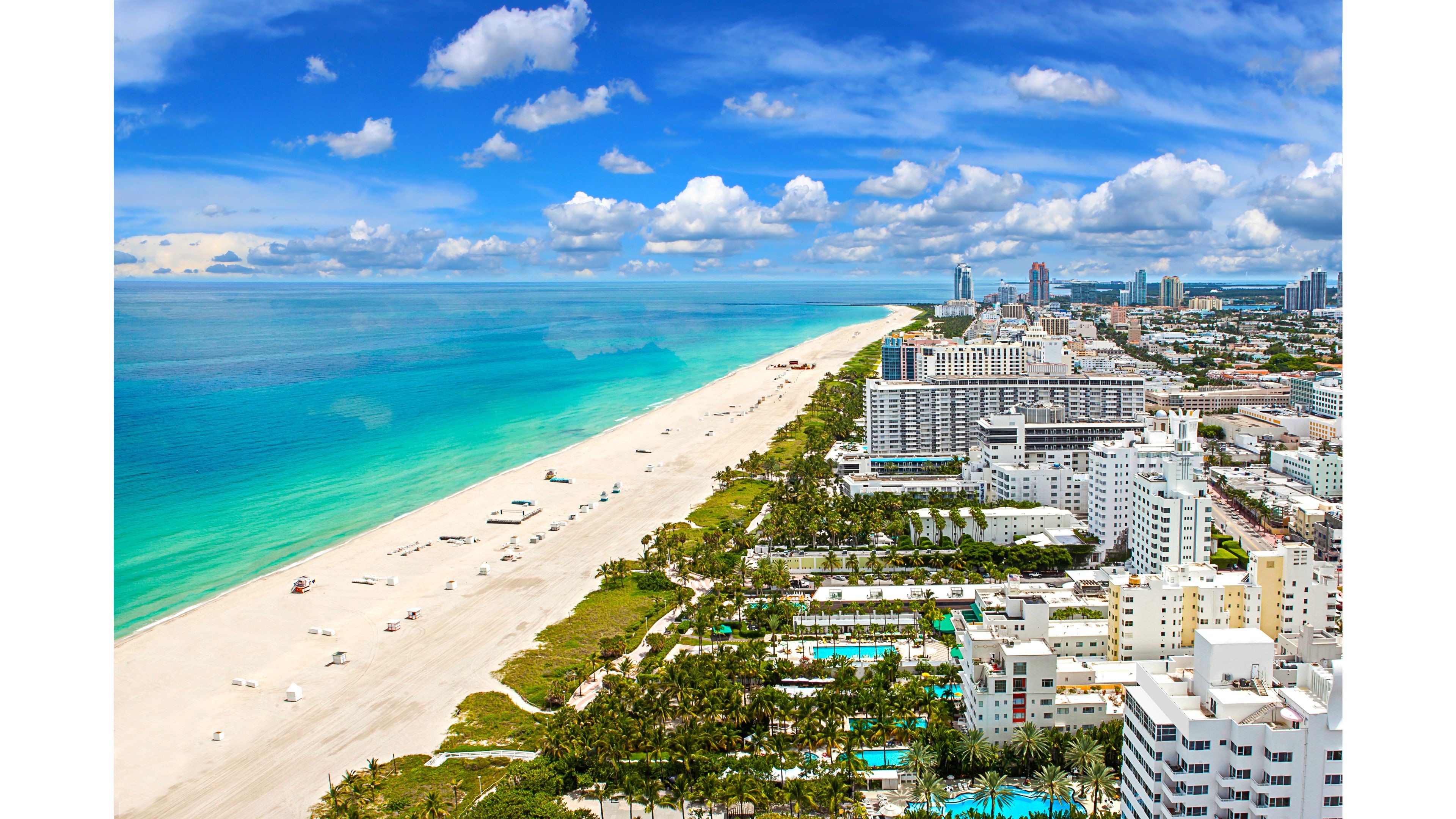 Aerial view of Miami Beach, Florida, showcasing the turquoise ocean, white sandy beach, and vibrant cityscape