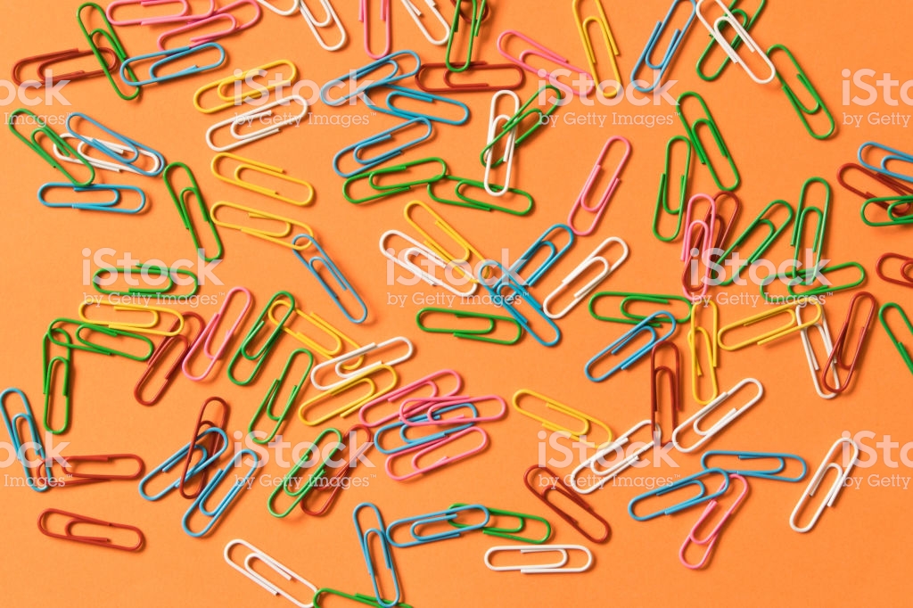 Many Colored Paper Clips On A Orange Background The Concept Of