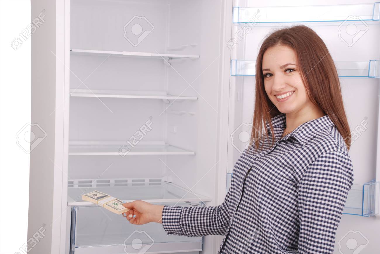 Young Girl Holding Dollars On The Refrigerator Background