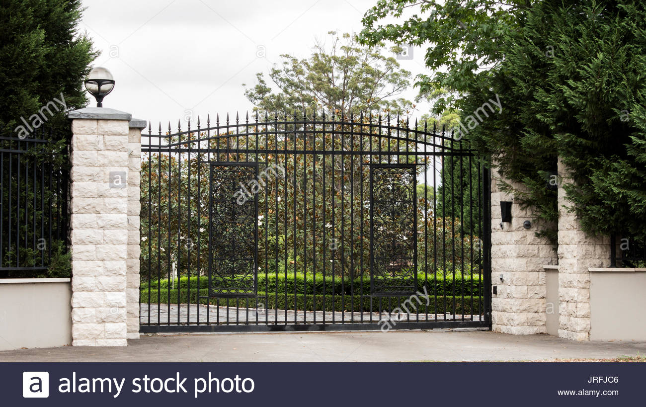 Black Metal Driveway Entrance Gates Set In Brick Fence With Garden