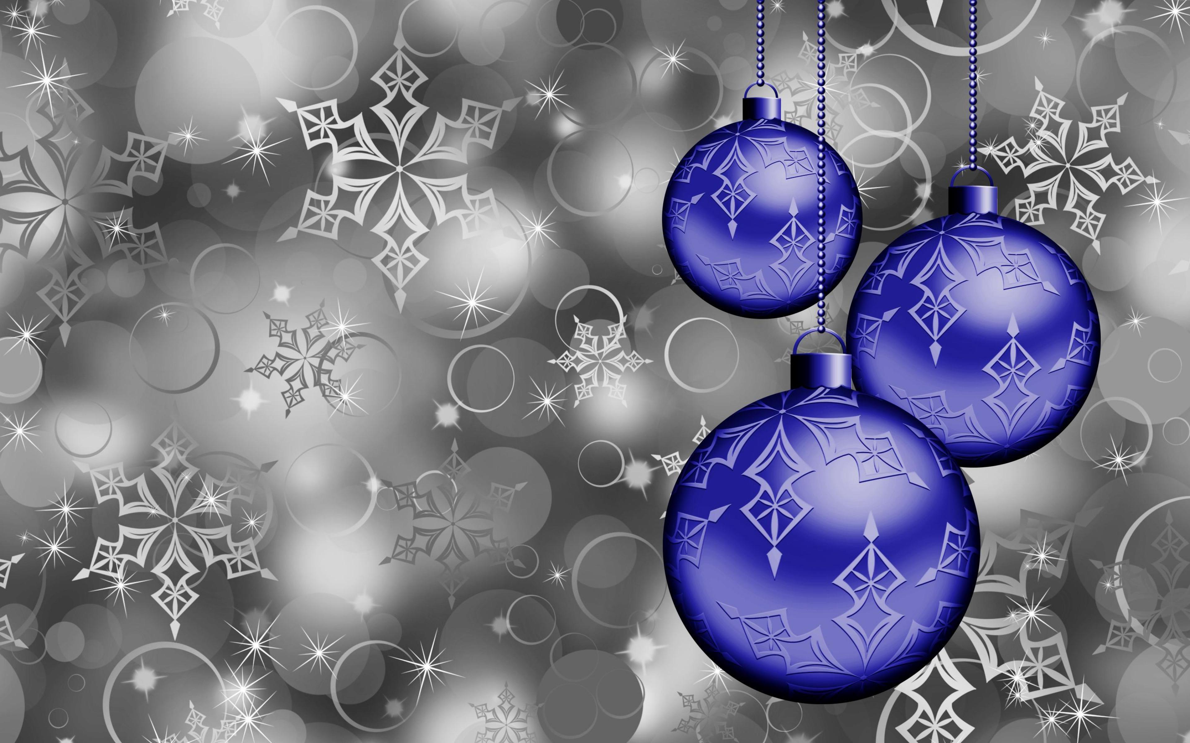 Three glossy blue Christmas ornaments with snowflake designs hanging against a backdrop of silver snowflakes and bokeh, creating a festive computer wallpaper