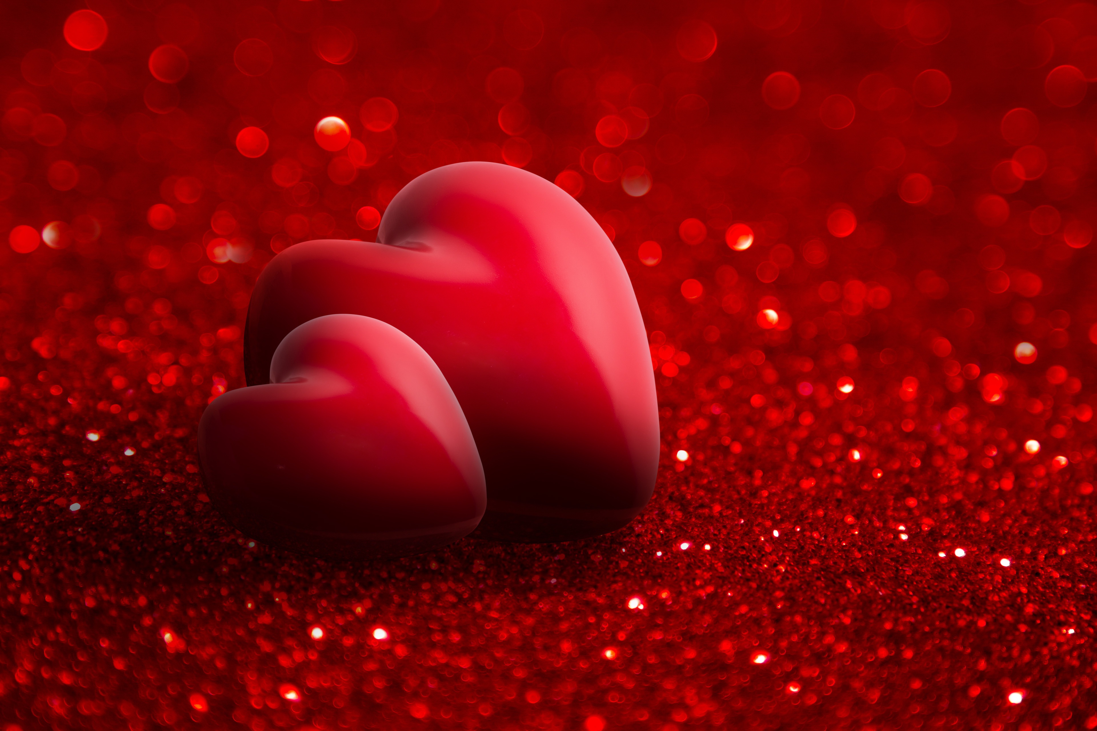 Two red hearts on a sparkling red background, perfect for Valentine's Day or romantic occasions