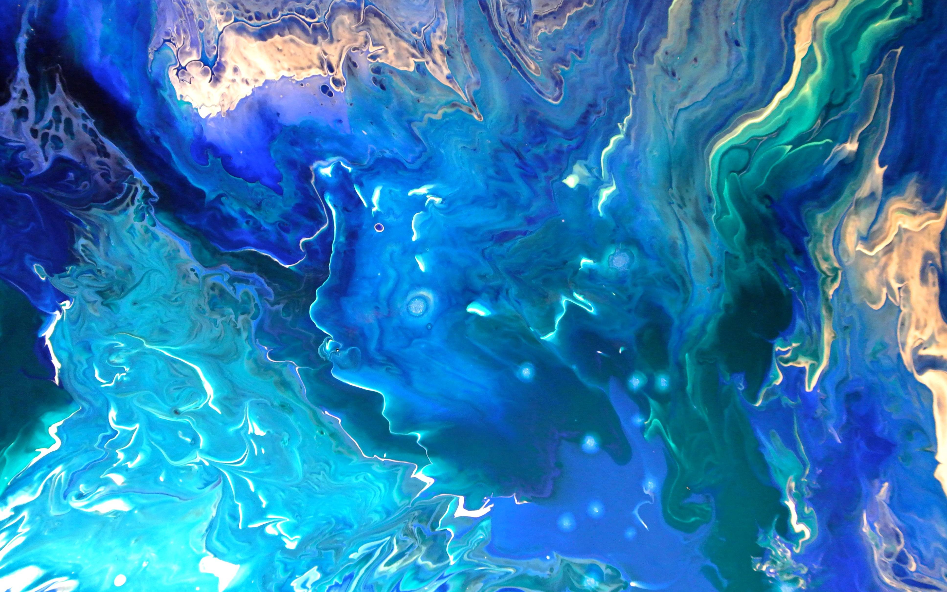 Abstract fluid art painting in shades of blue, teal, and gold, resembling an ocean or cosmic scene
