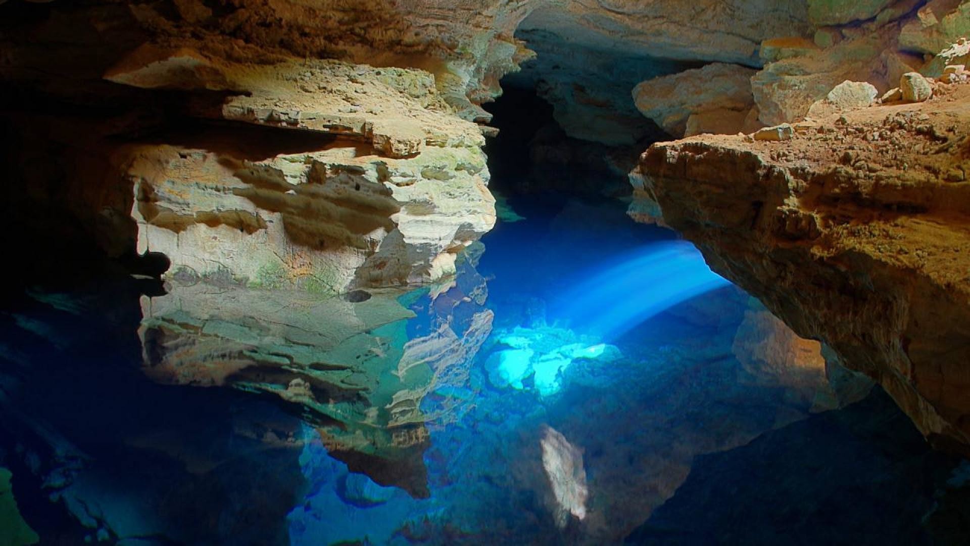 A breathtaking view of a subterranean lake in a cave, illuminated by a beam of light, creating a magical, otherworldly scene