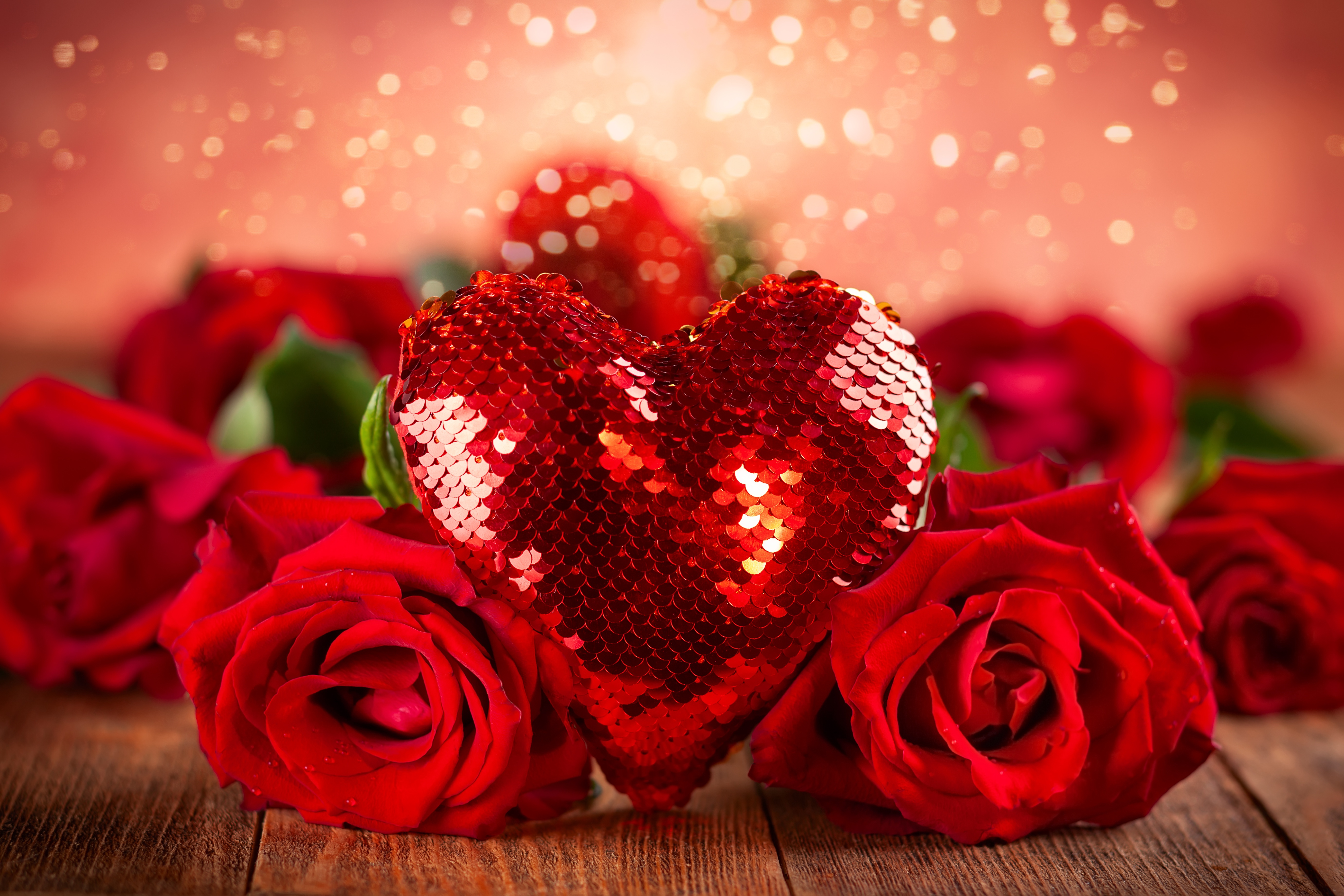 Red roses and a sequined heart decoration on a wooden surface, creating a romantic Valentine's Day scene