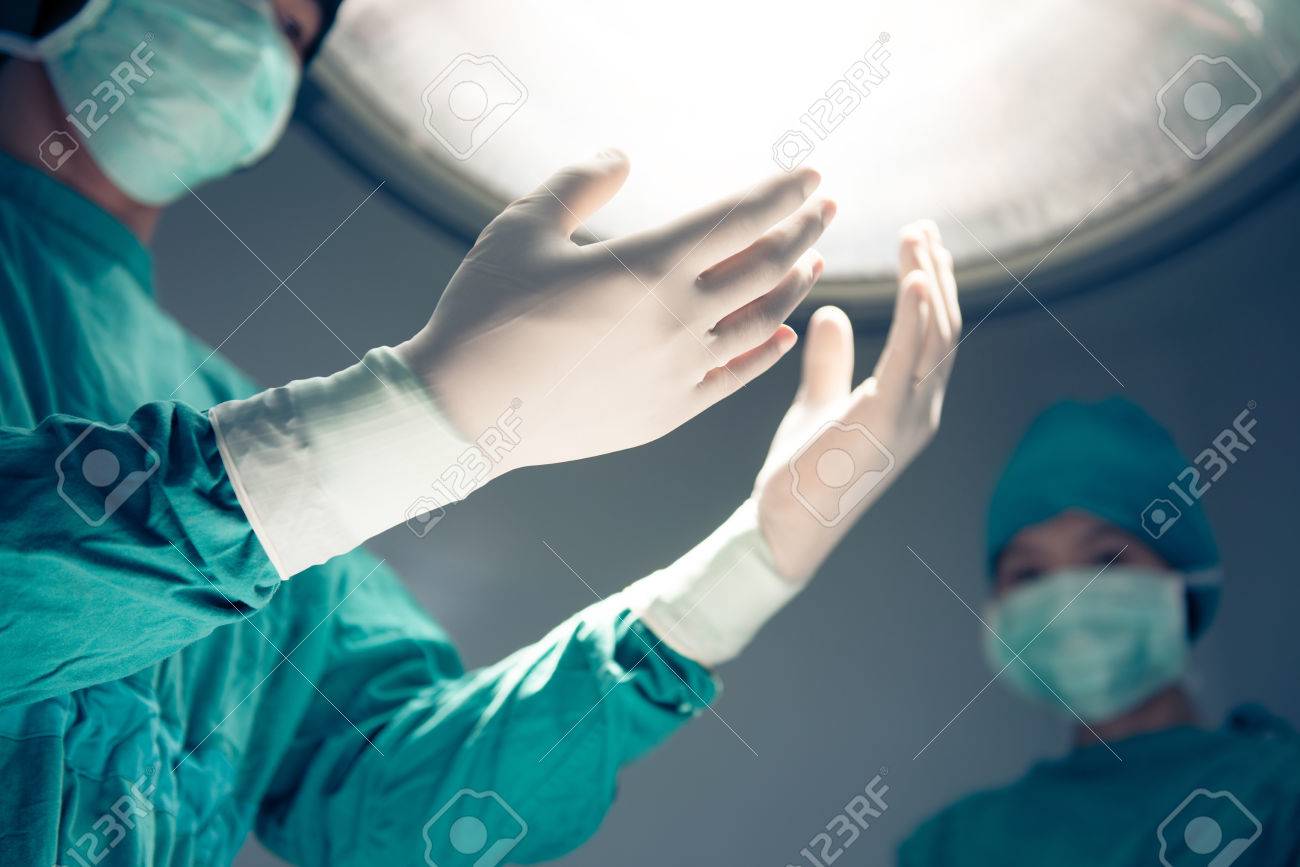 Hands In Surgical Gloves On Operation Room Background Of