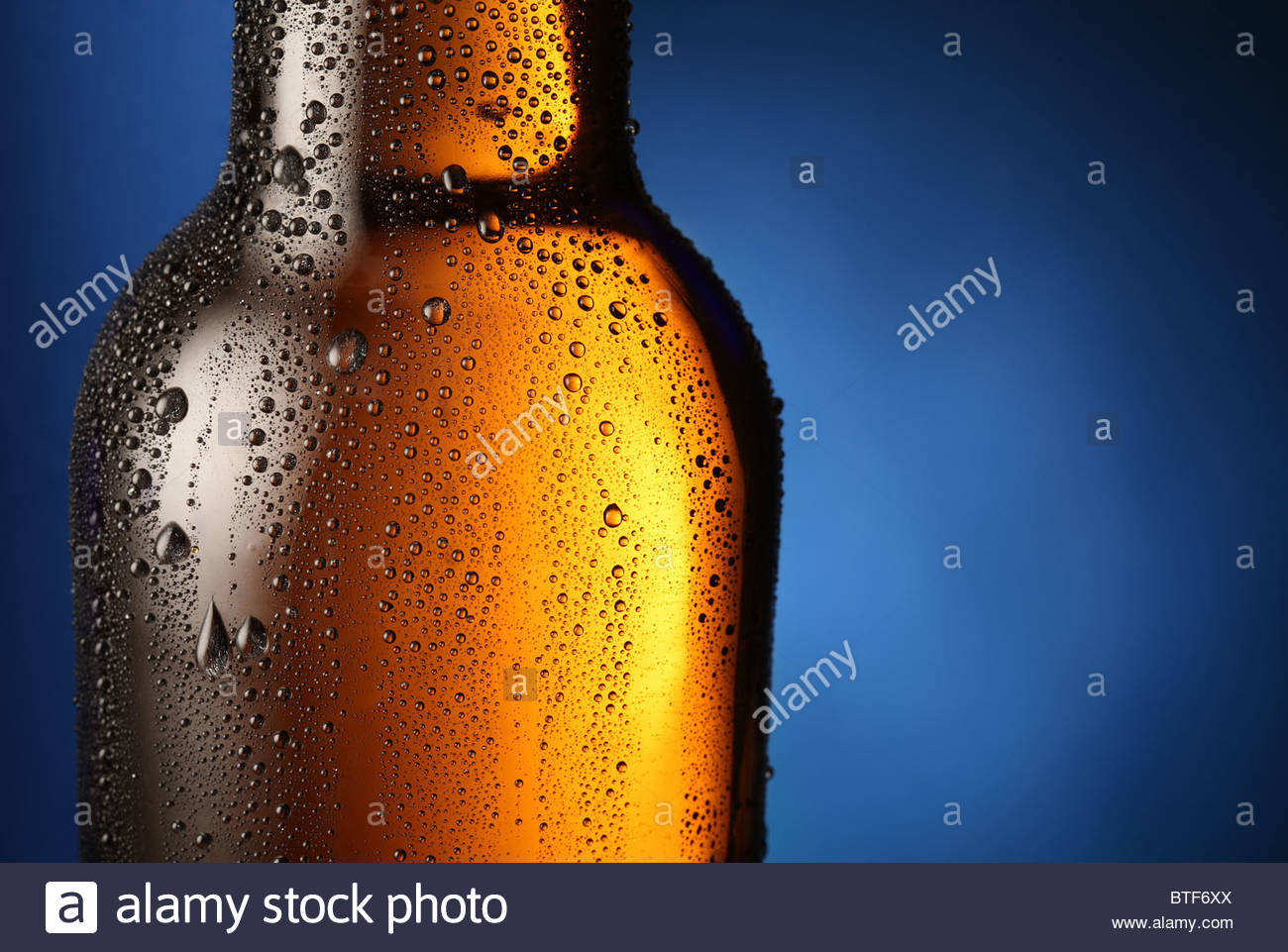 Bottle of beer with drops on a blue background Close up part of
