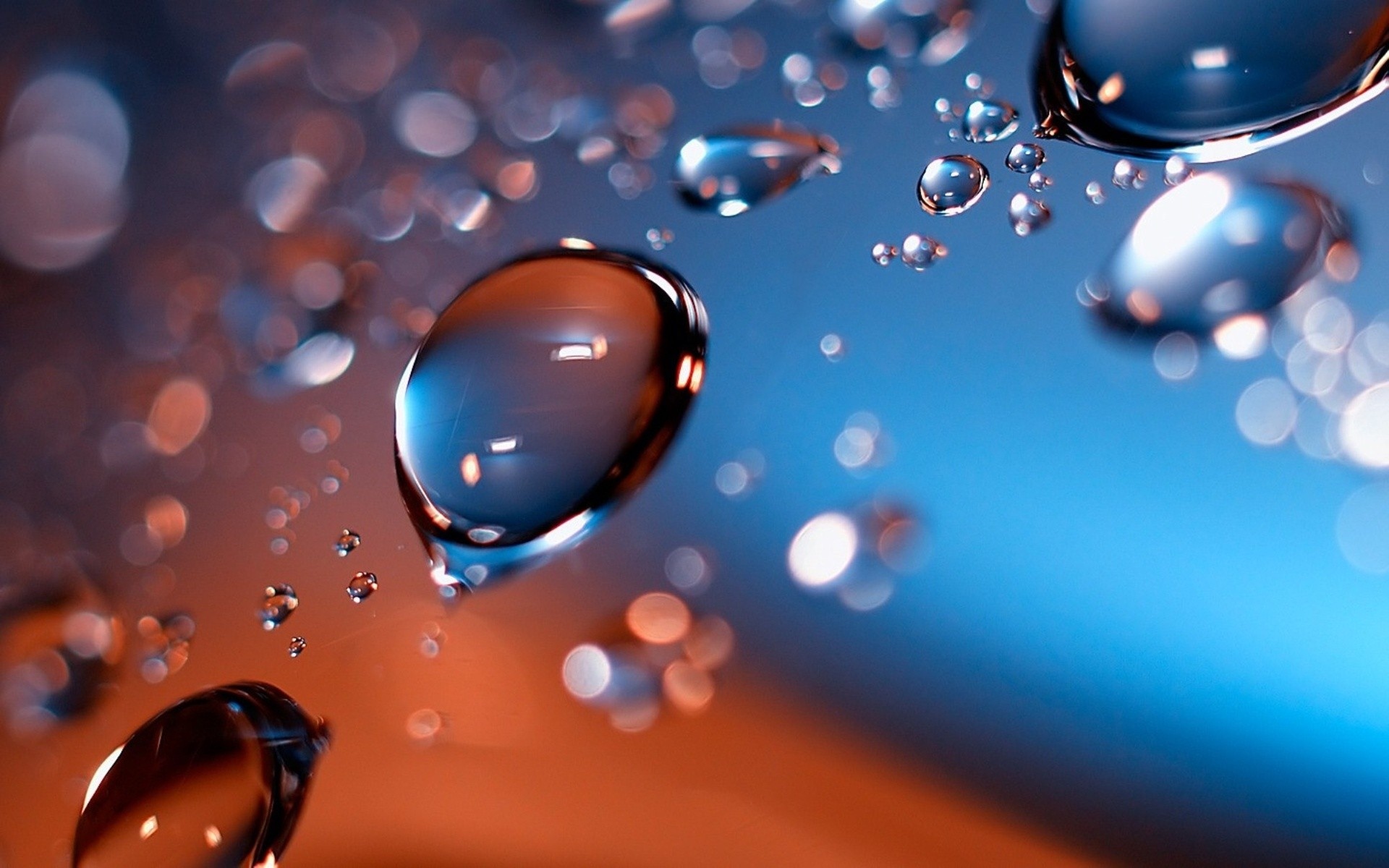 Close-up of water droplets on a surface with a vibrant blue and orange background