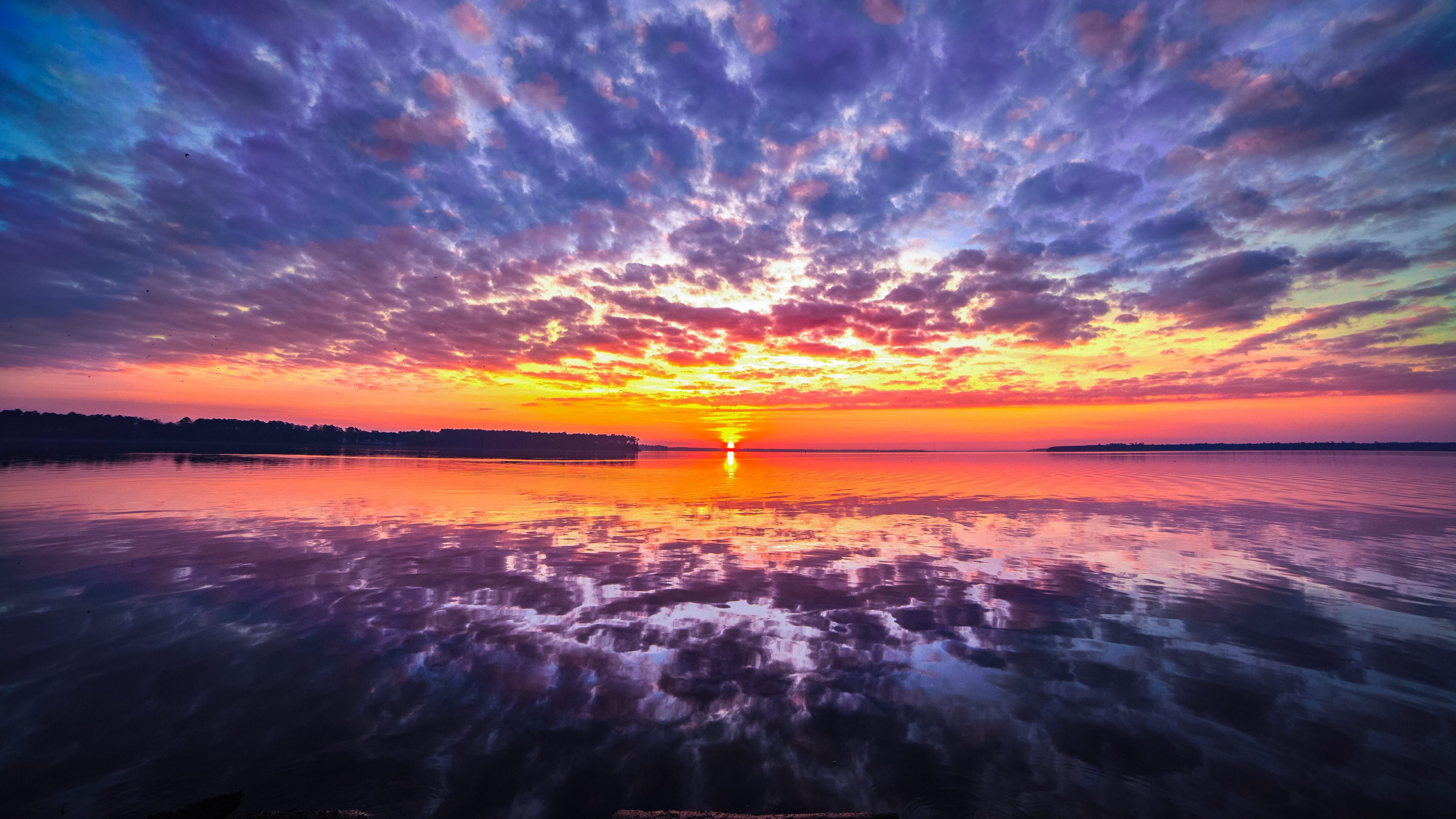 Vivid 4K Sunset over Calm Water with Colorful Cloud Reflections