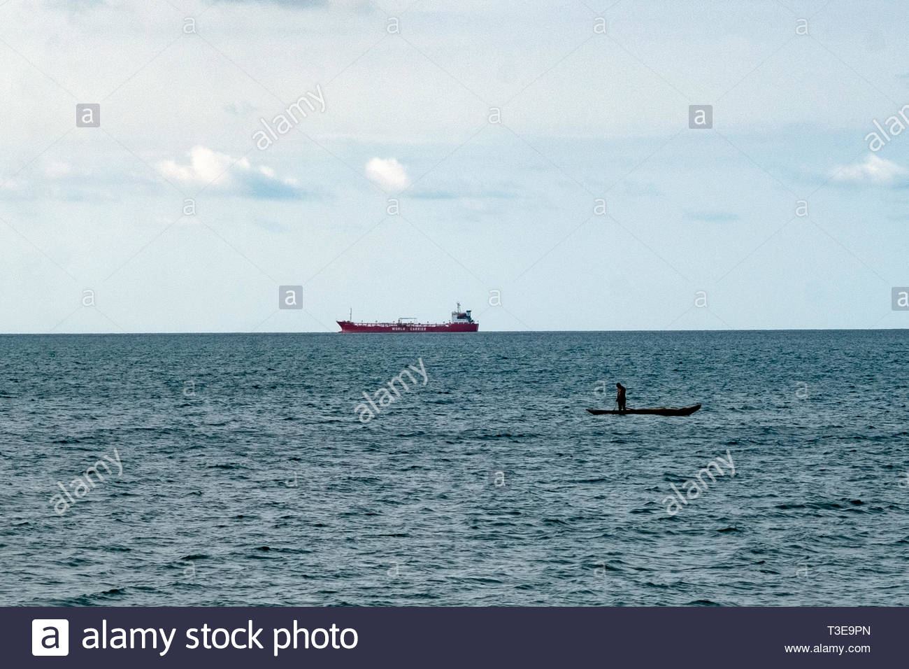 A Fisherman In Dugout Canoe Tends His S With Large Ship
