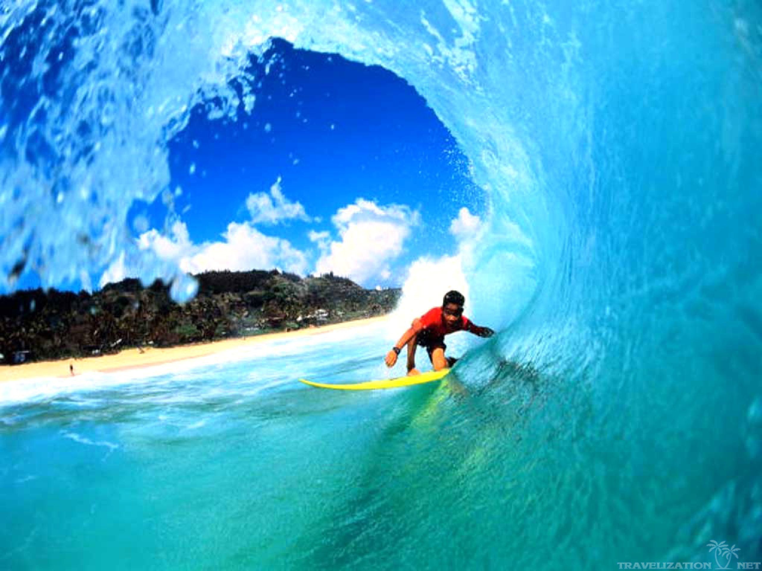 A surfer riding a bright yellow surfboard inside the curl of a turquoise wave, with a tropical beach in the background