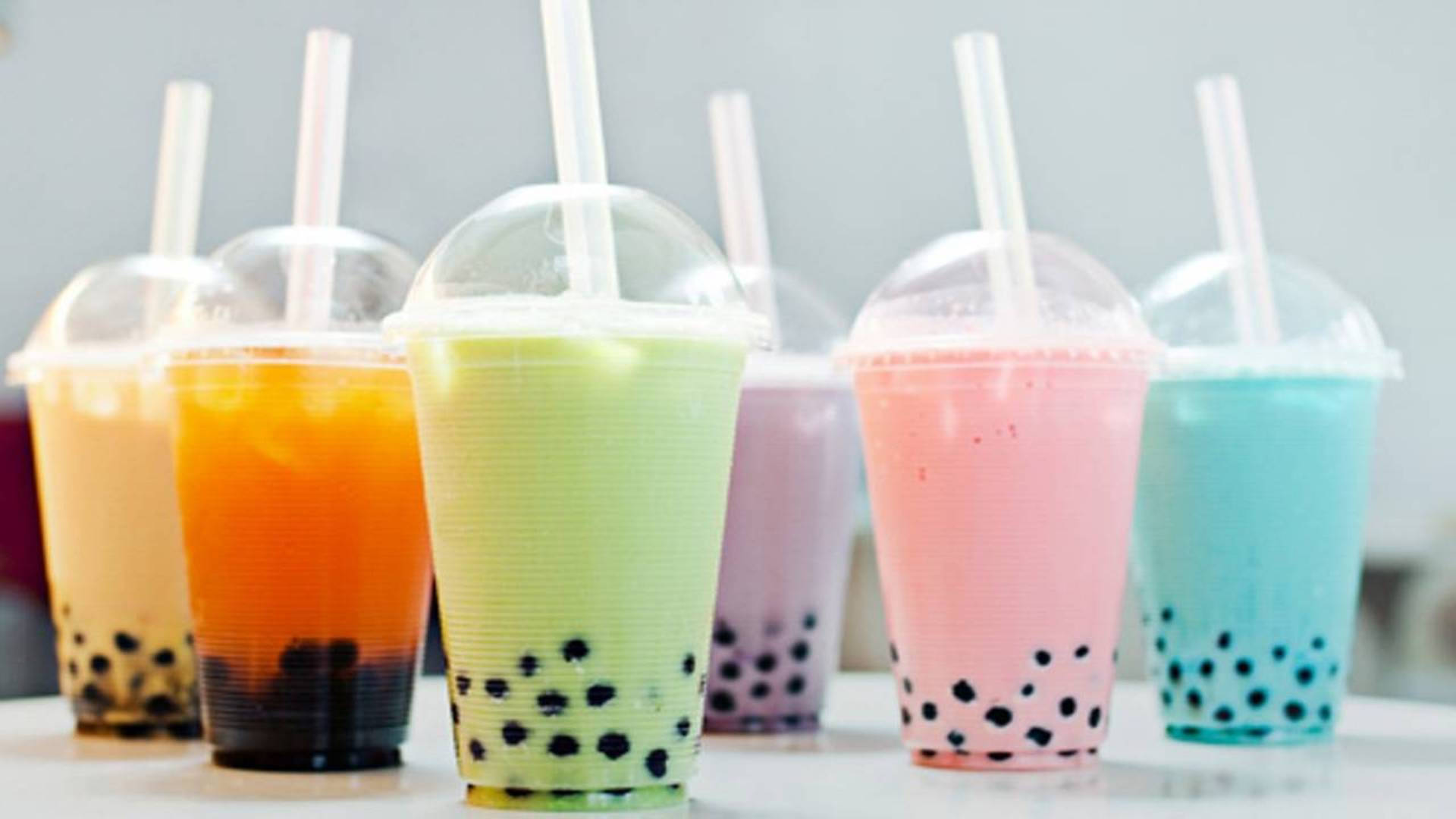 Assortment of colorful boba tea drinks in plastic cups with straws